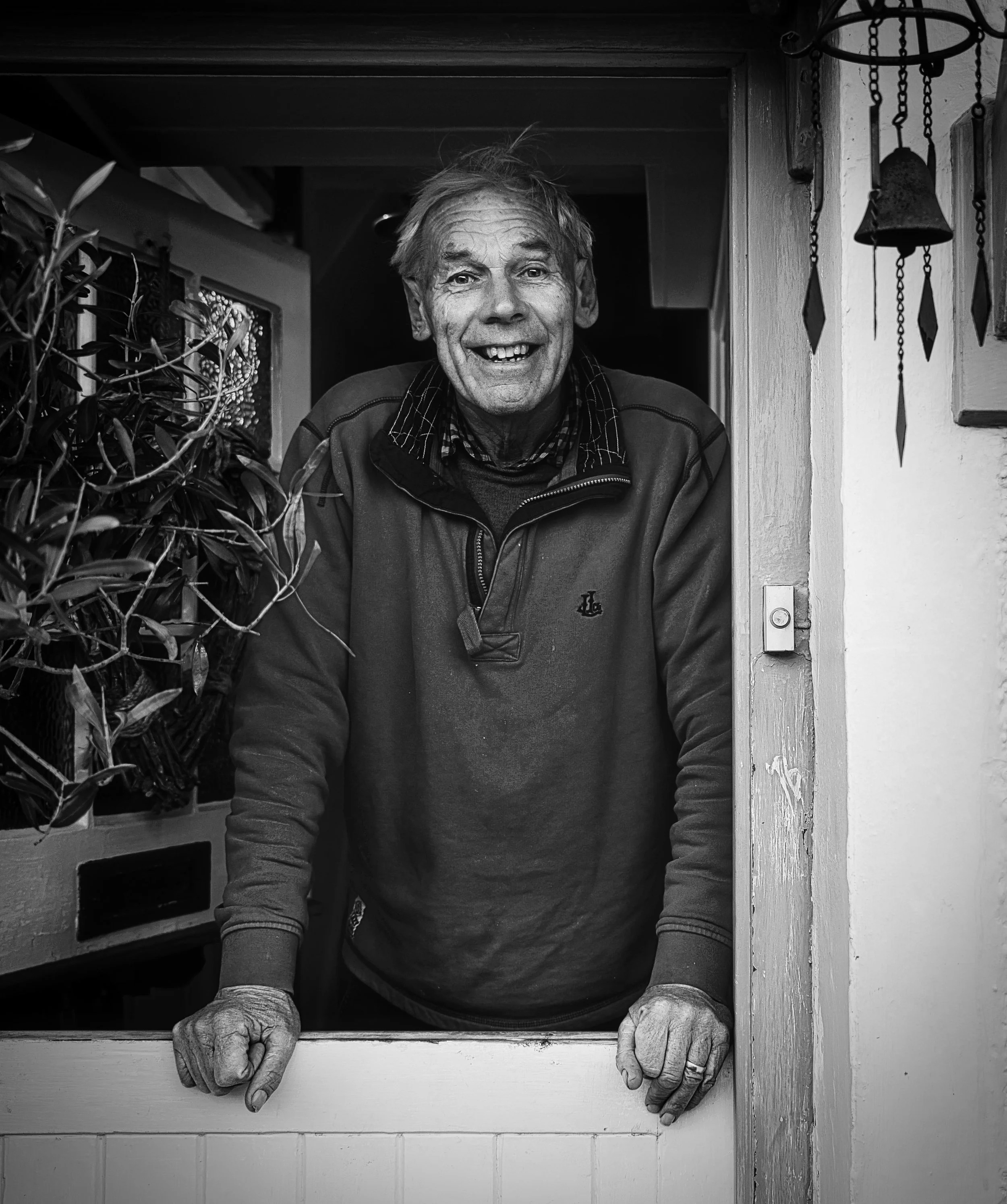 Black and white portrait of a smiling man standing in a doorway