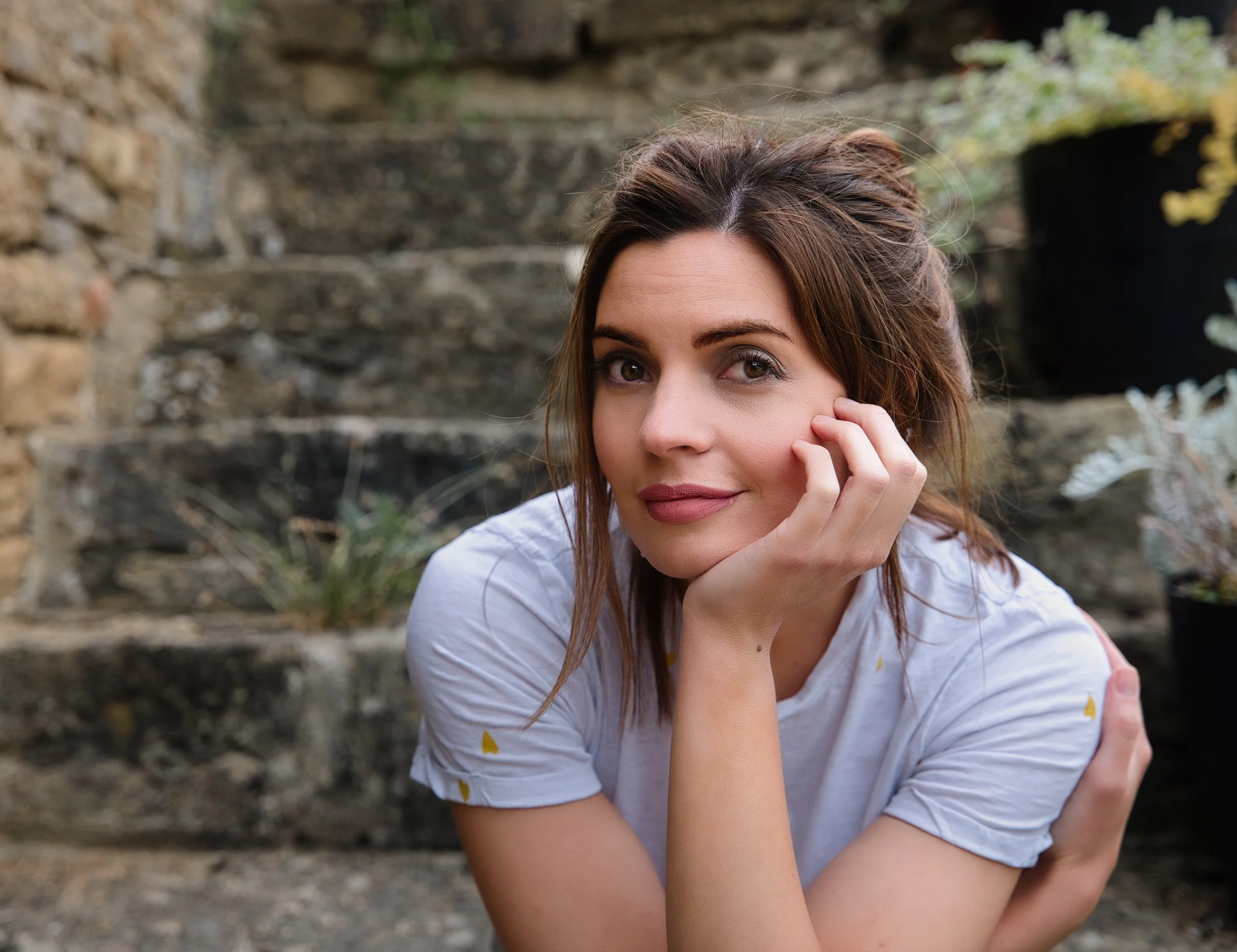 Outdoor portrait of a woman sitting beside a stone wall