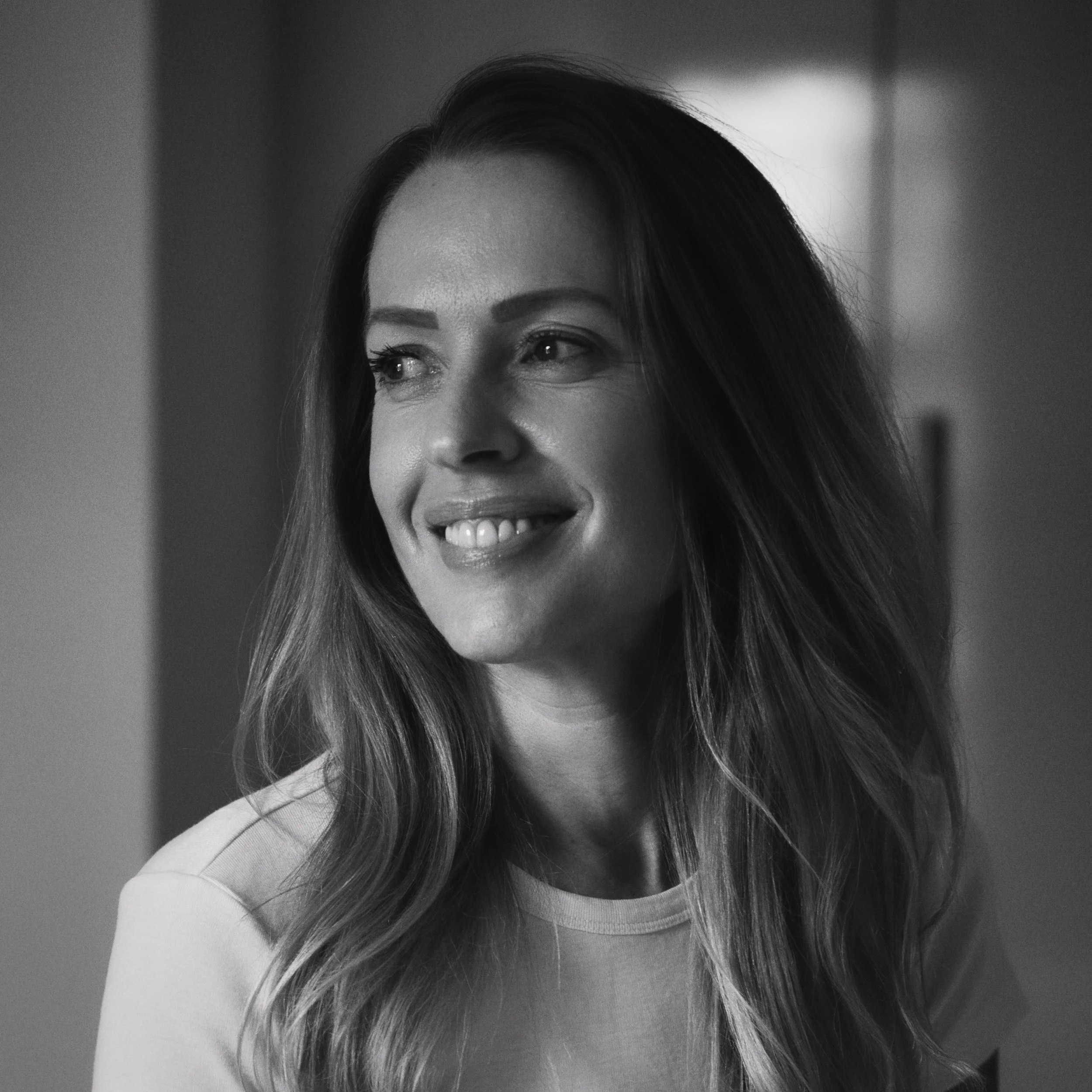 Black and white portrait of a smiling woman in soft window light