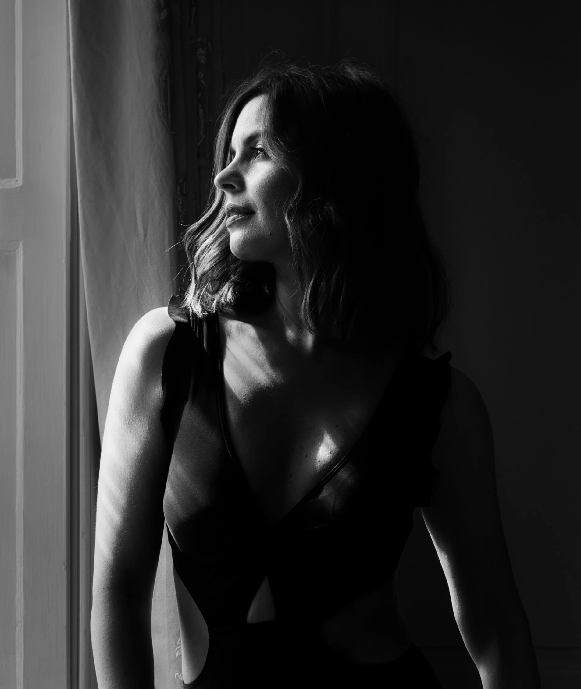 Black and white portrait of a woman in dramatic window light