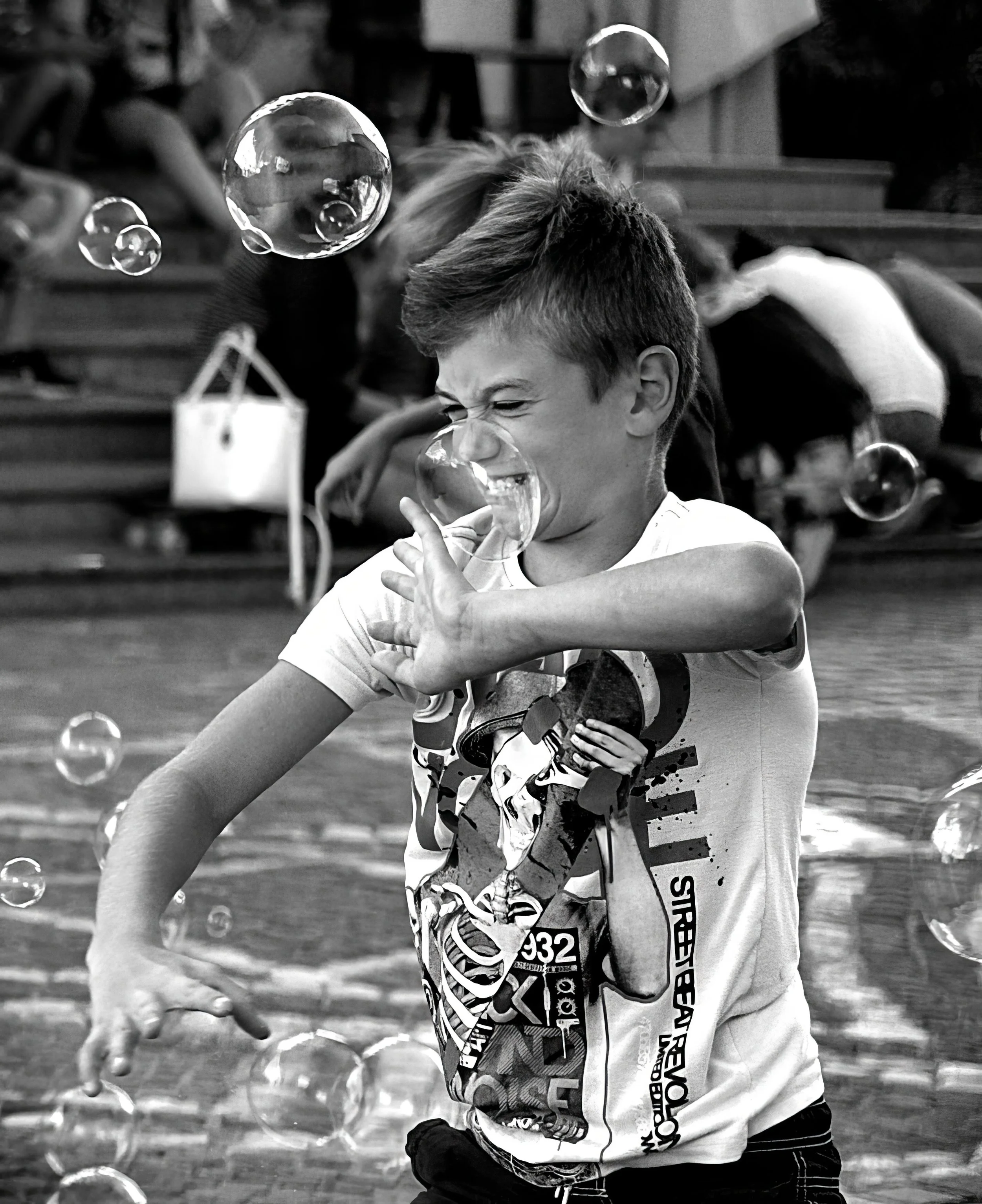 Black and white photograph of a child reacting to floating bubbles in Ljubljana