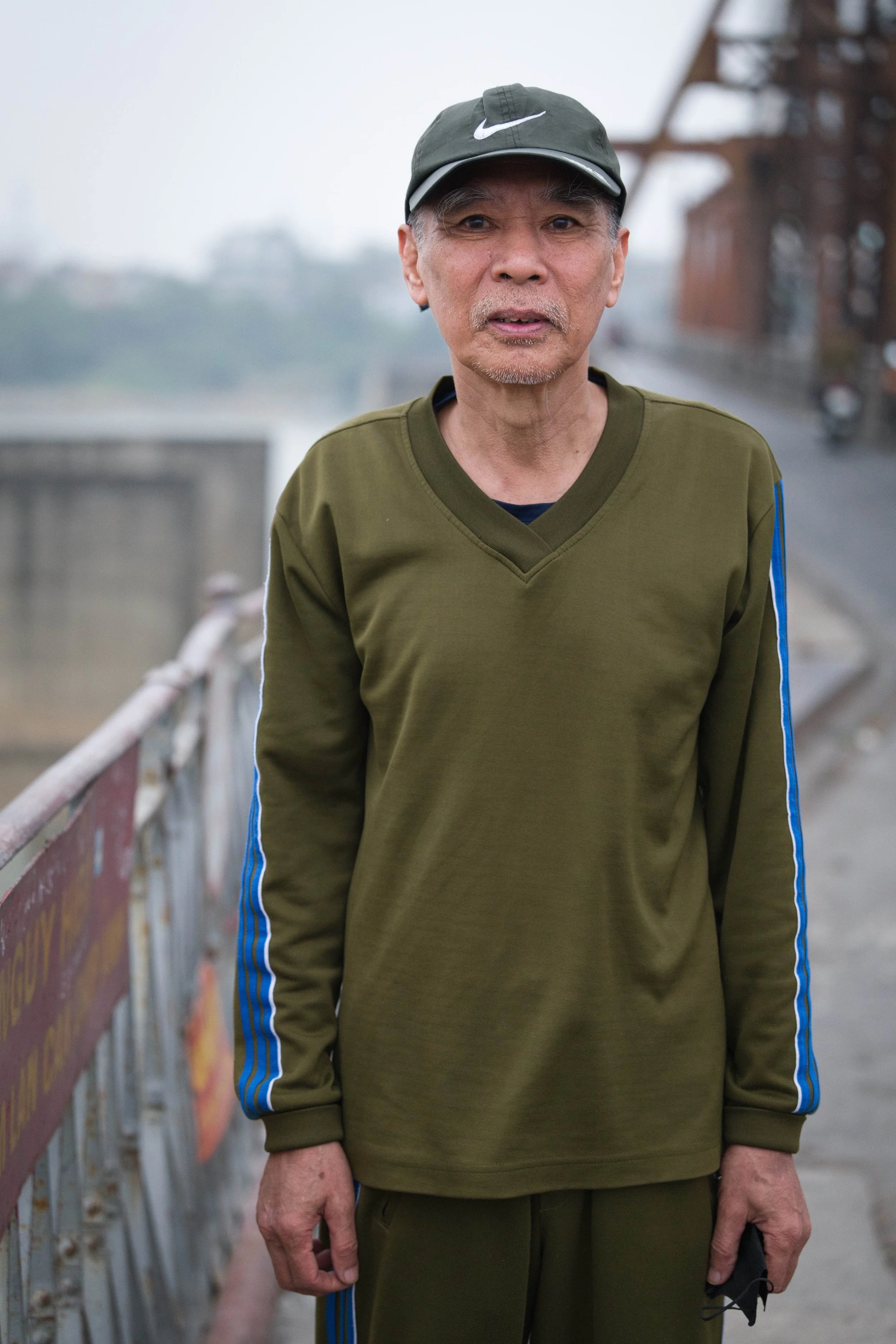 Portrait of a man standing on Long Bien Bridge in soft overcast light