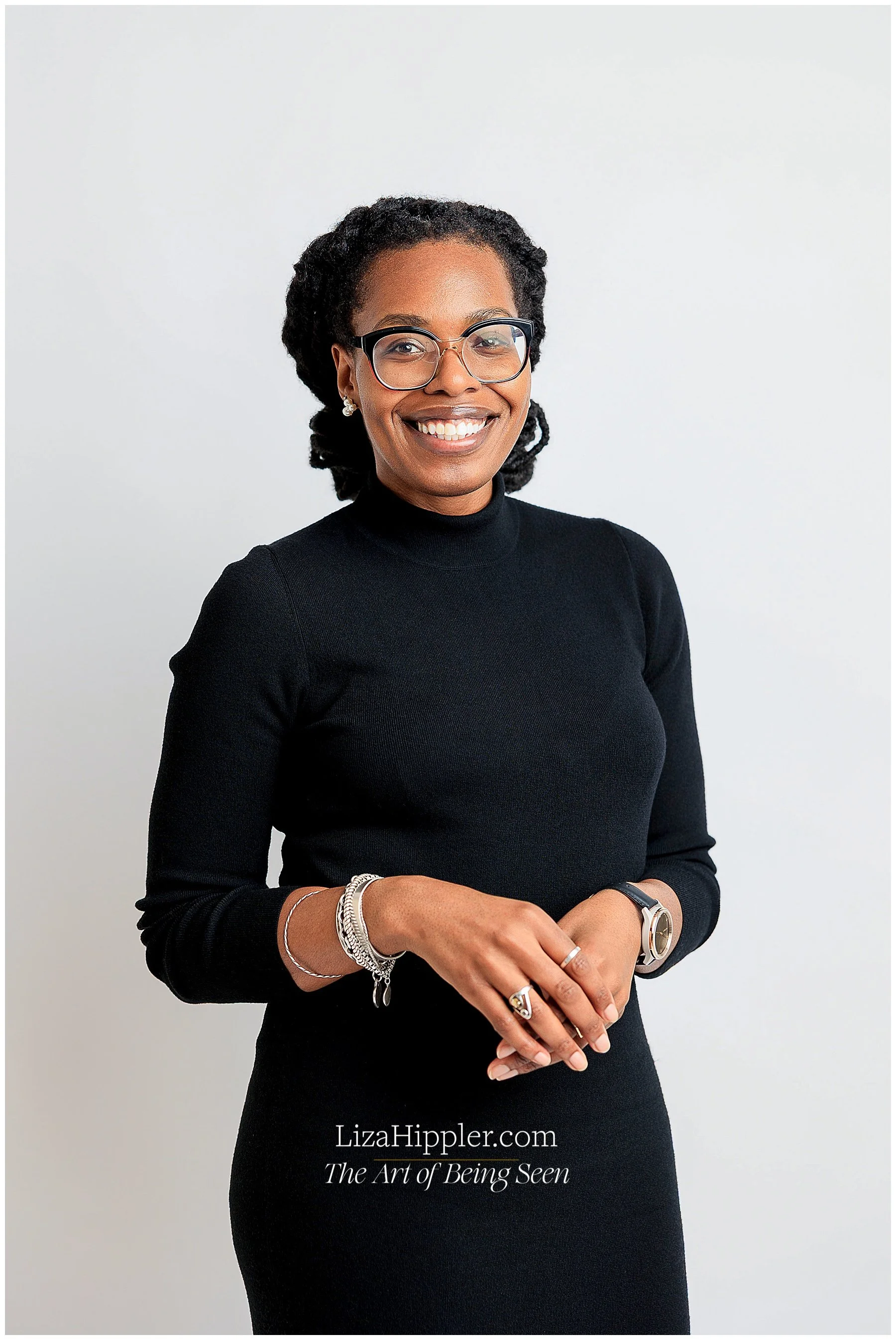 Professional brand photo of a black woman with dreads standing up wearing a black turtleneck dress on a white background. Nashville brand photography Liza Hippler.