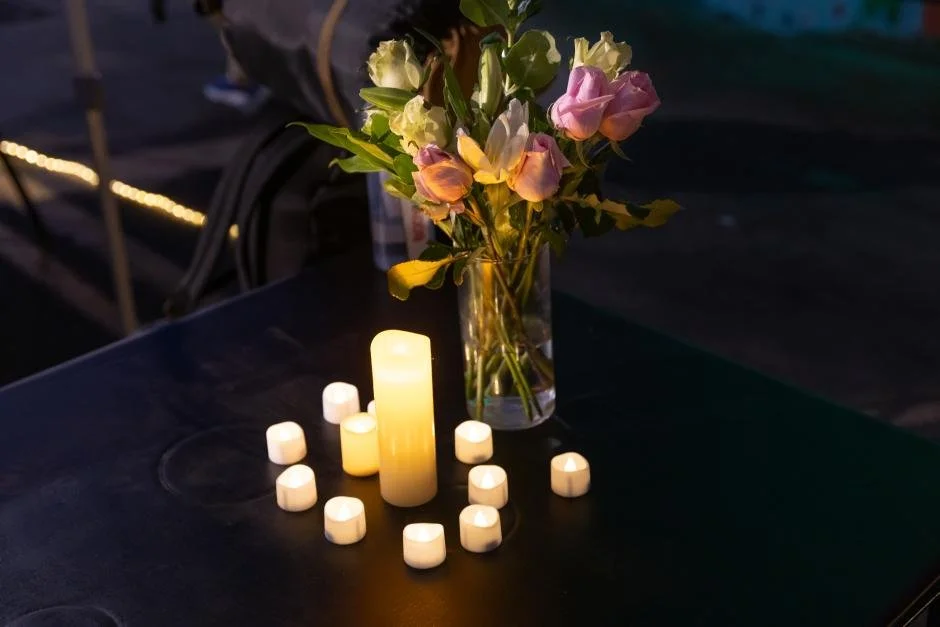 A bouquet of flowers is arranged next to candles in the evening