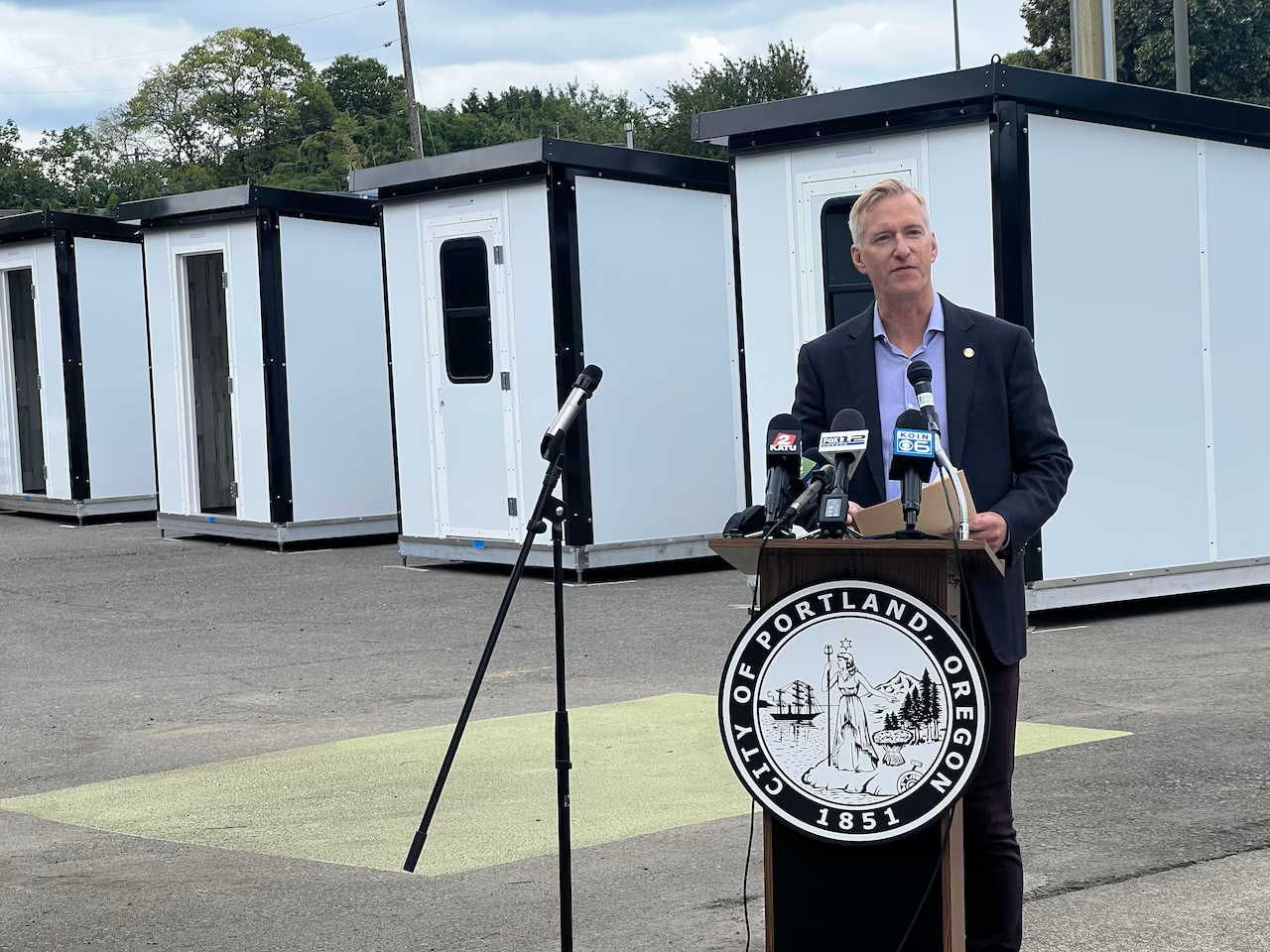 Portland Mayor Ted Wheeler stands in front of a tiny home village