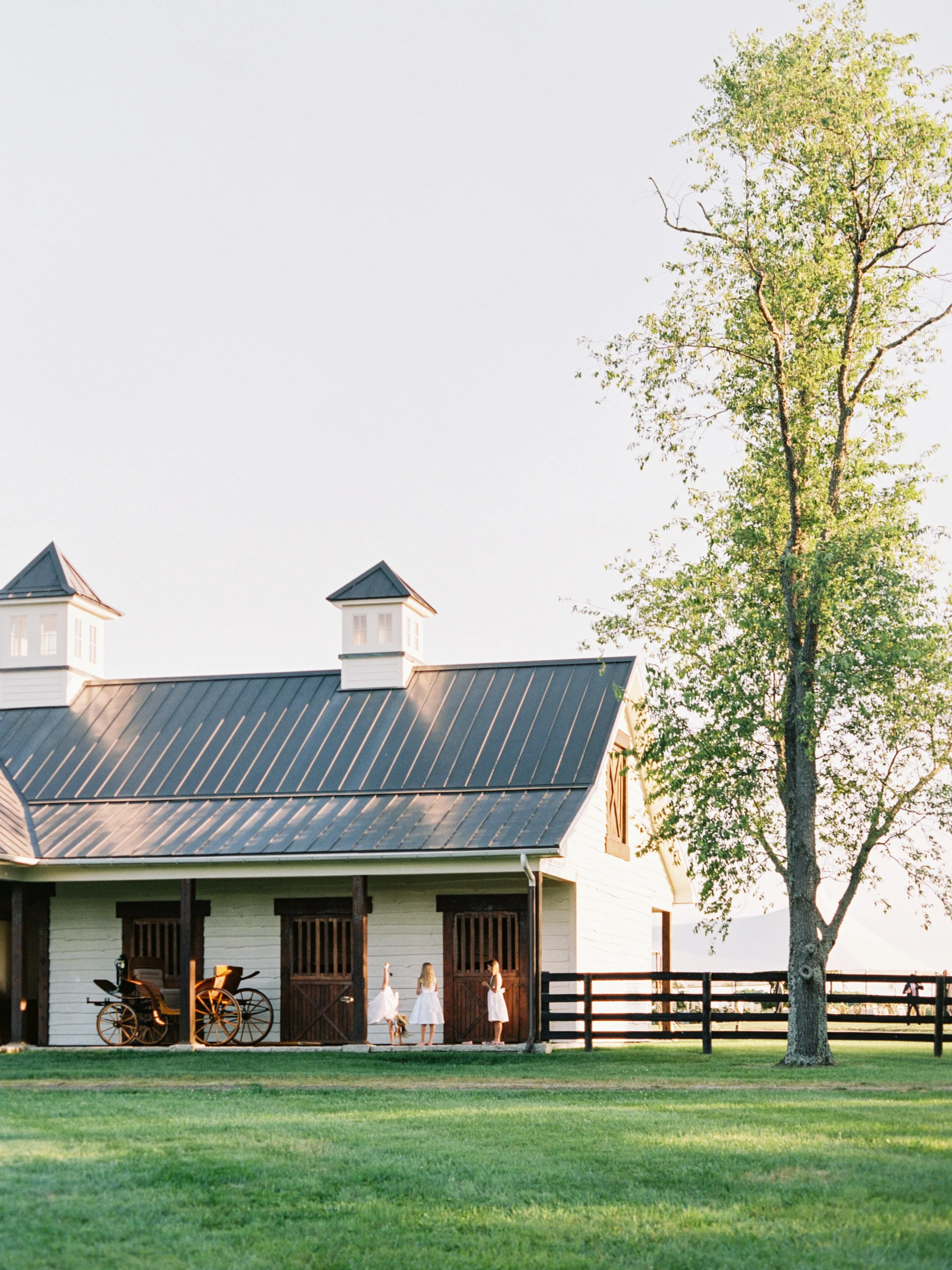 Flower girls playing by family's horse farm barn at the wedding cocktail hour