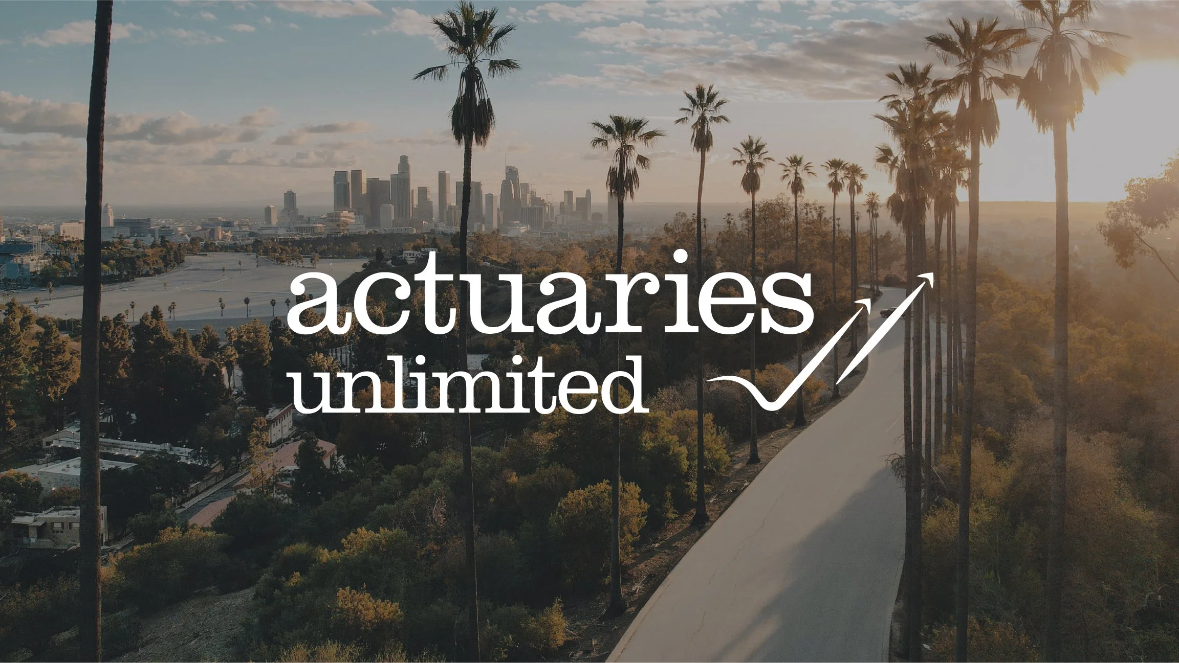 Sunset over the Los Angeles skyline with palm trees and a winding pathway in a park, featuring the words 'actuaries unlimited' and an upward arrow graphic.