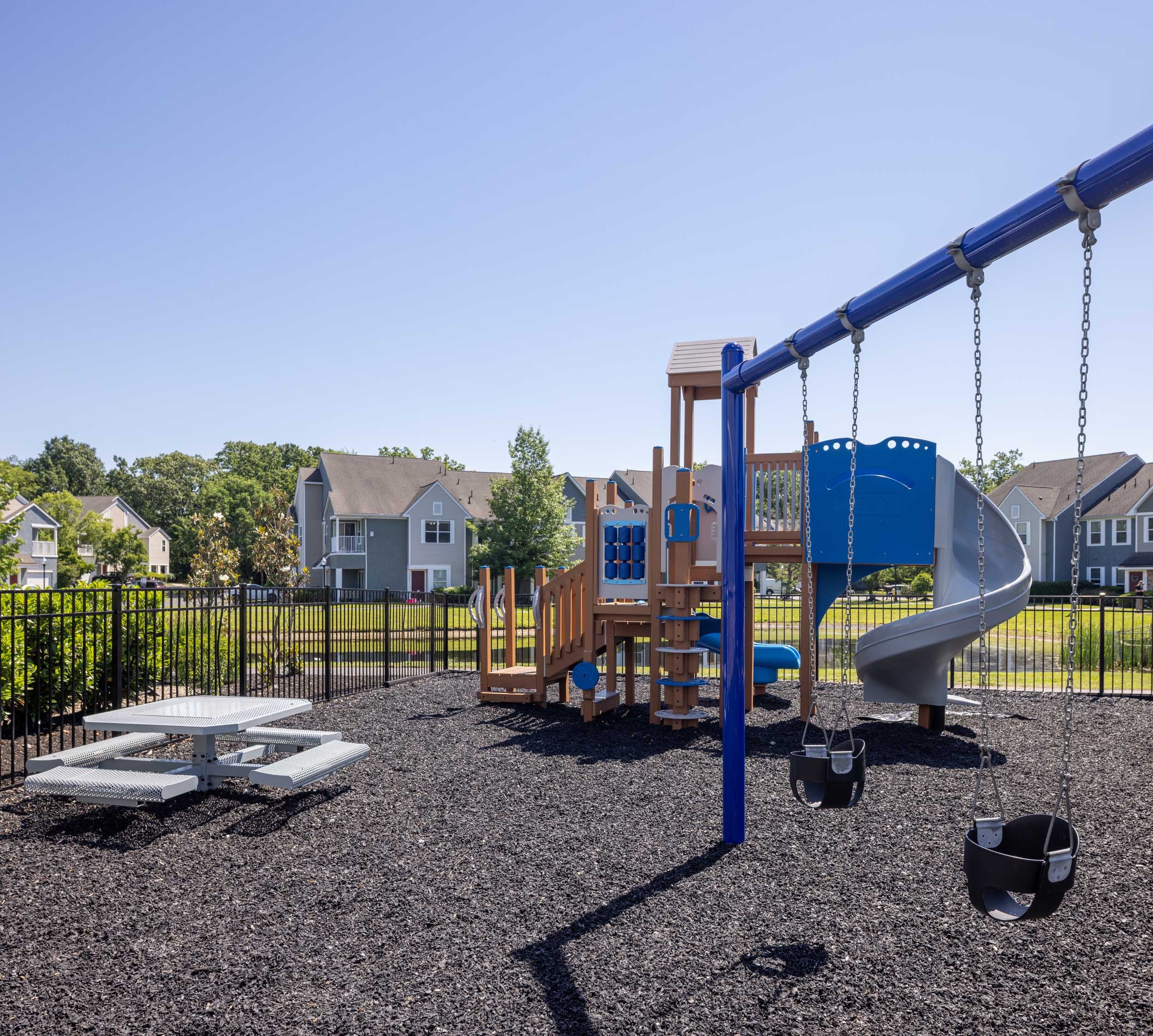 Playground with swings, slide, and climbing equipment in a residential neighborhood.
