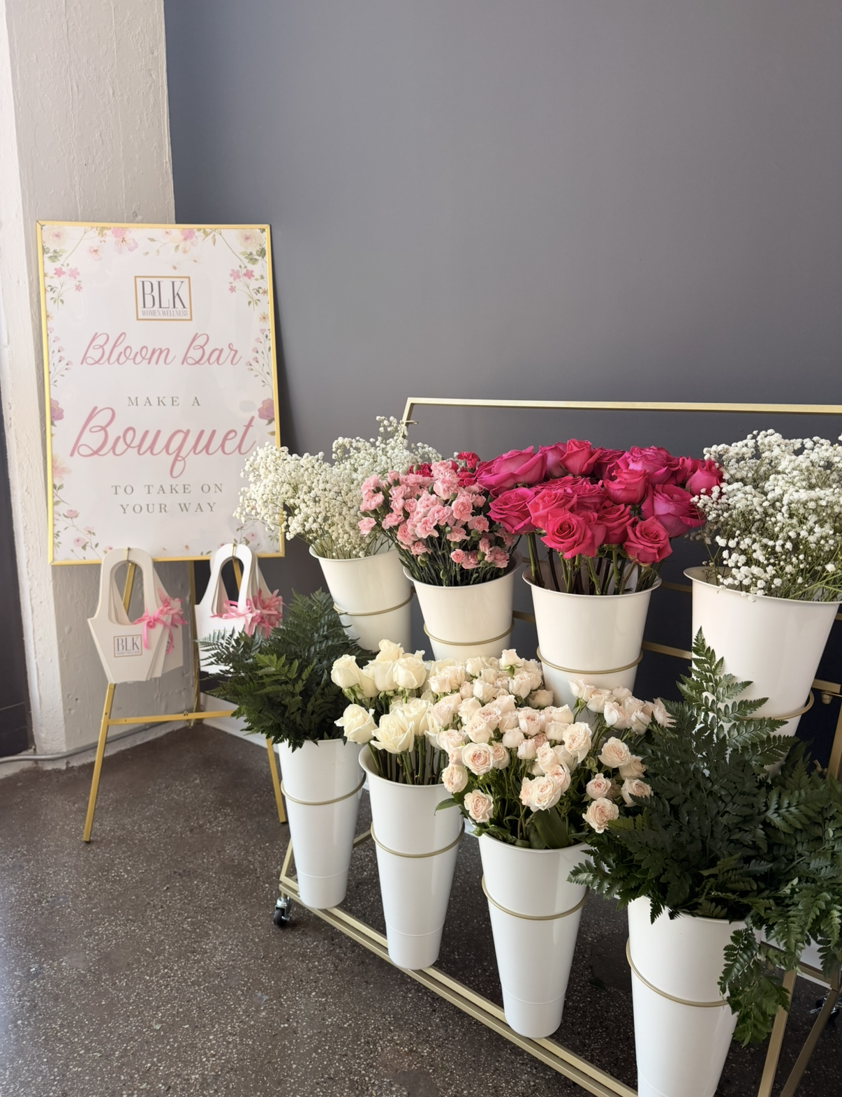 A woman lying on a floor in a library, reading a book with shelves of books around her. The text 'Book Club' is overlaid, and a logo in the top right corner reads 'BLK Women Wellness'.