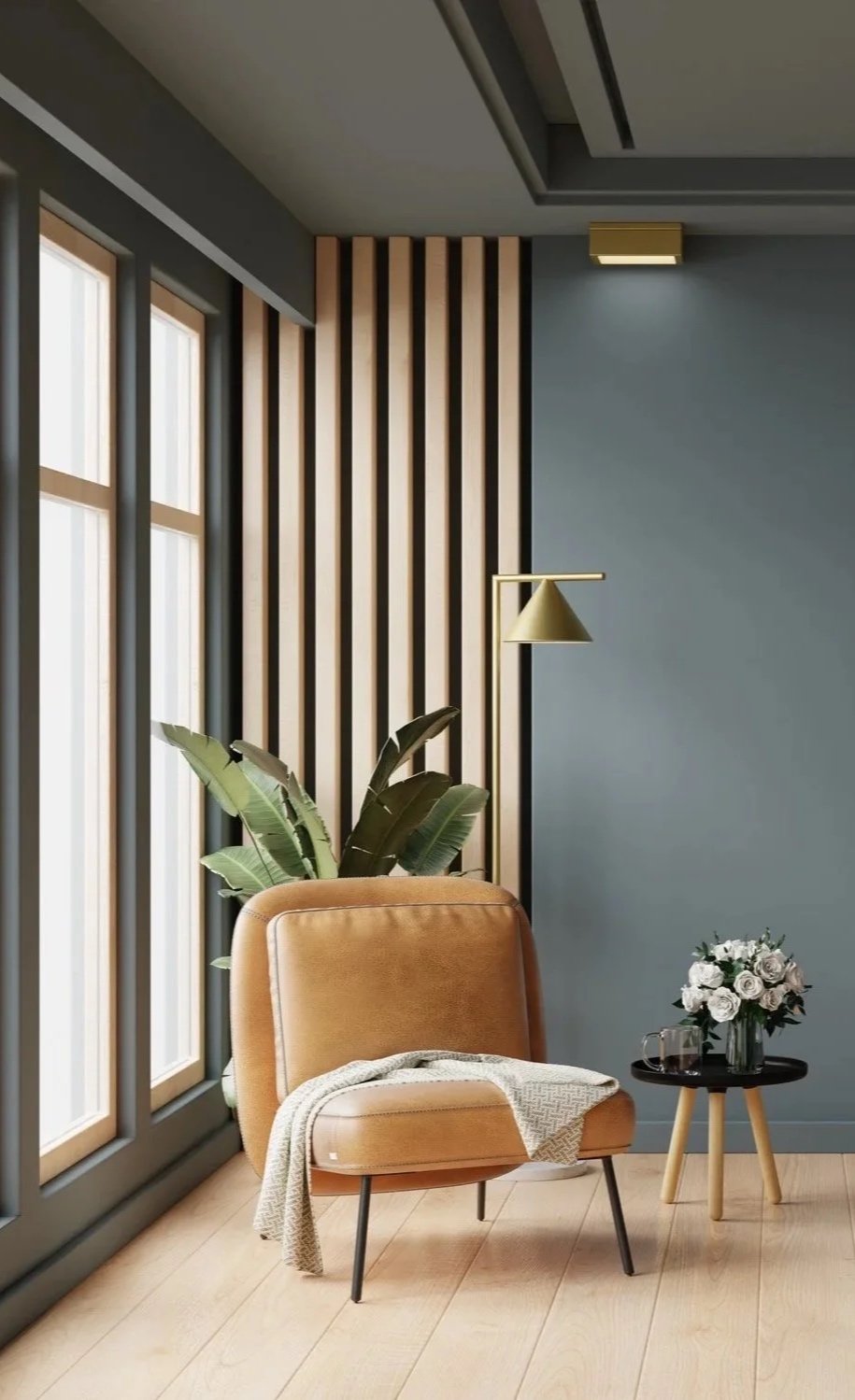 Modern interior with large windows, a tan chair with a blanket, a black side table with white flowers, a green floor lamp, green plant, and wooden wall paneling.