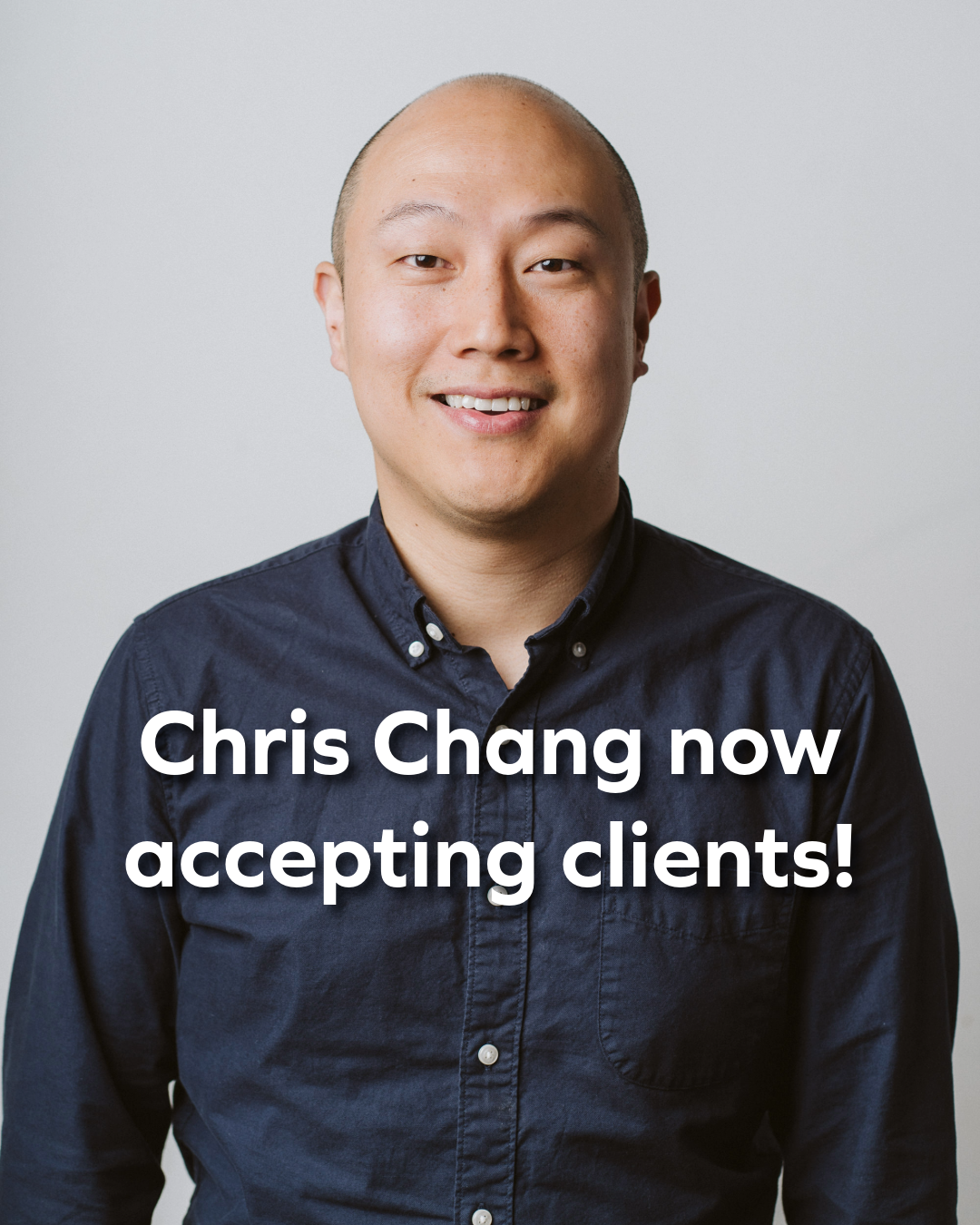 A smiling man with a shaved head wearing a dark blue button-up shirt, standing against a light gray background. Text overlay says "Chris Chang now accepting clients!"