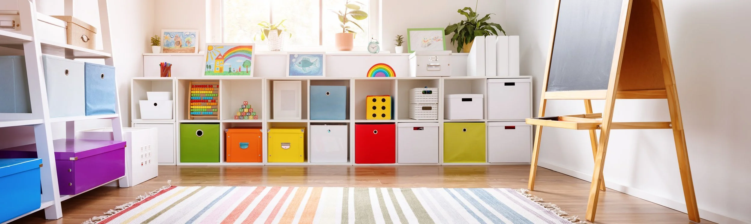 Colorful children's playroom with storage cubes, artwork, plants, and a chalkboard