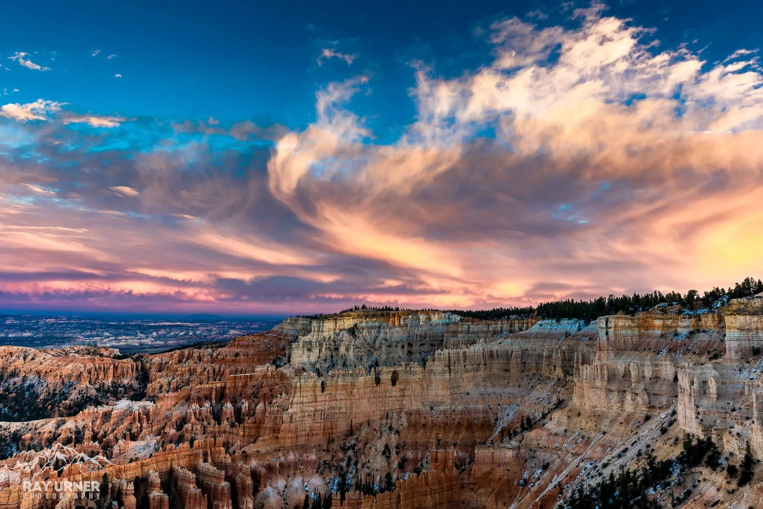 Sunset over the Grand Canyon with colorful sky and snow patches on the canyon walls.