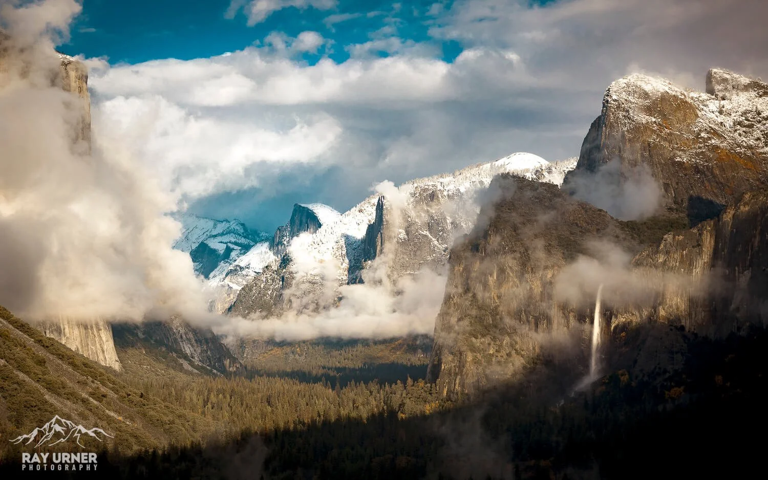 Snow-capped mountains with clouds and a waterfall in the Yosemite National Park landscape