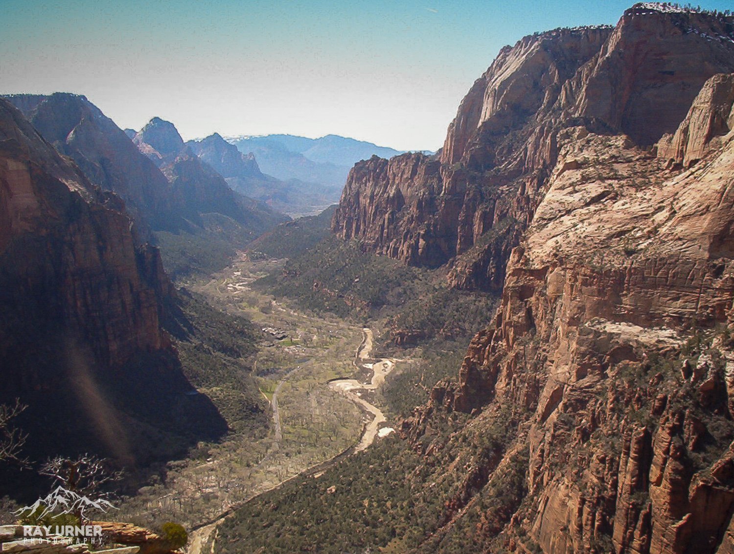 Aerial view of a river flowing through a canyon with tall red and brown cliffs on both sides.