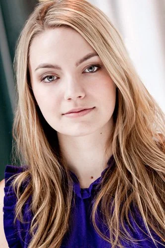 Model headshot sample featuring a blue eyed, long blonde model wearing a frilly royal blue top