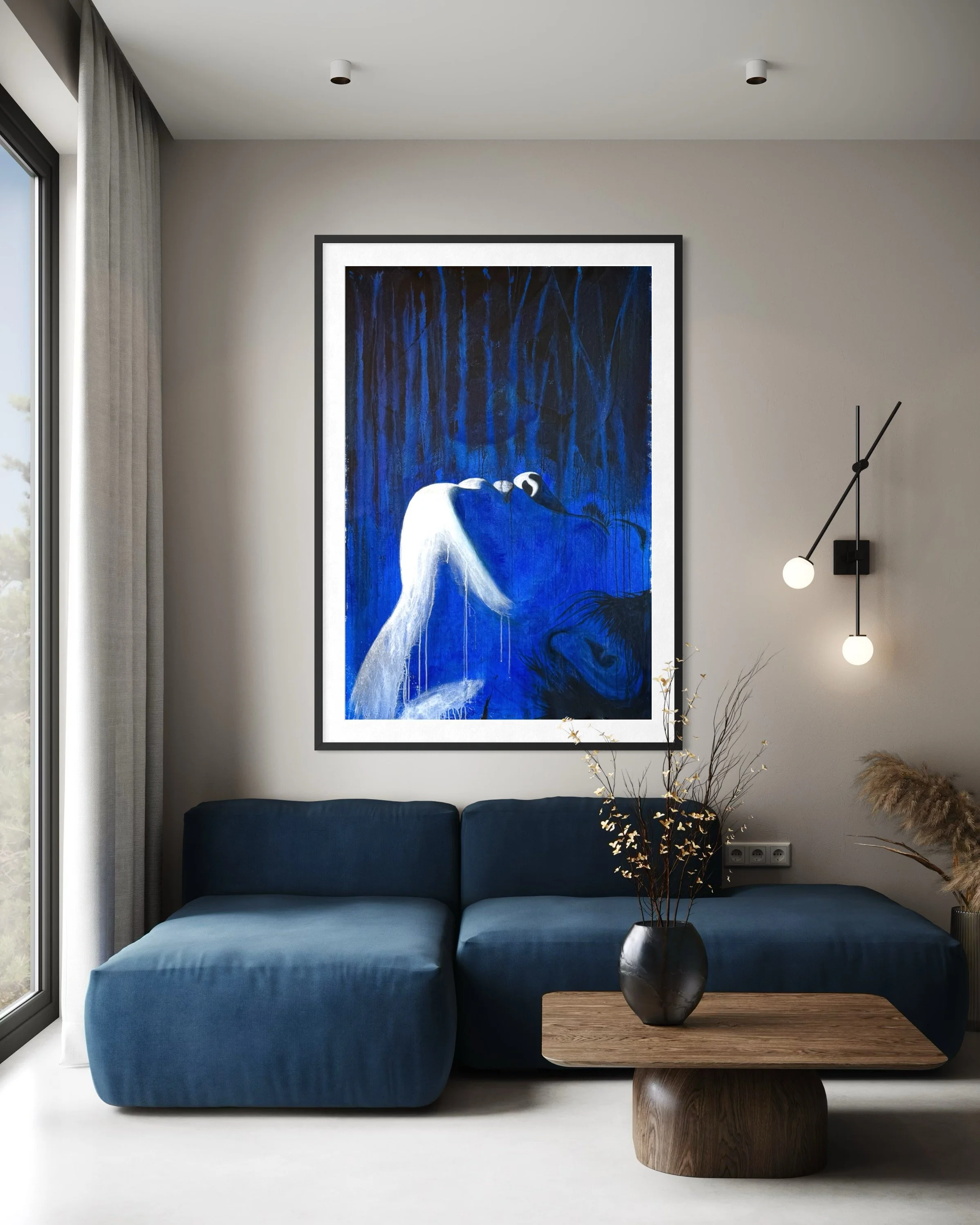 Modern living room with a large framed painting of a heron in blue tones hanging above a blue sofa. There is a wooden coffee table with a black vase and decorative branches, a wall-mounted lamp with two bulbs, and a large window with curtain letting in natural light.