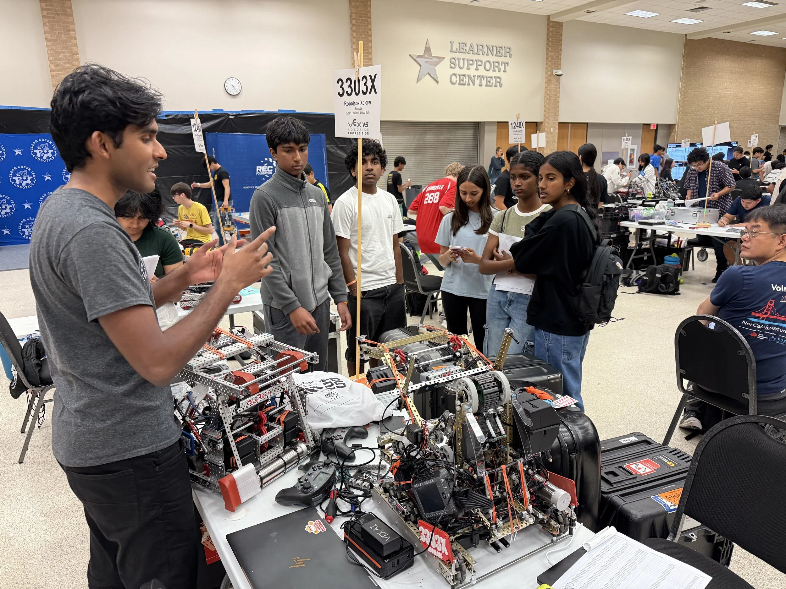 Robolabs VEX AI team presenting their competition robots and discussing their designs with other students at a VEX robotics event.