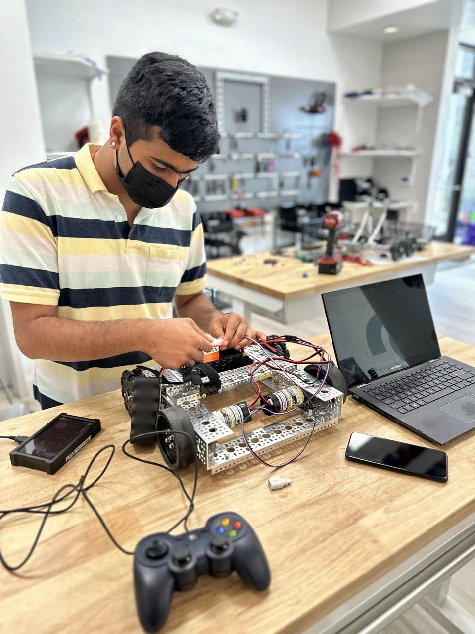 A student focused on wiring the electronics of his FIRST Tech Challenge robot, ensuring proper connections for motors and sensors.