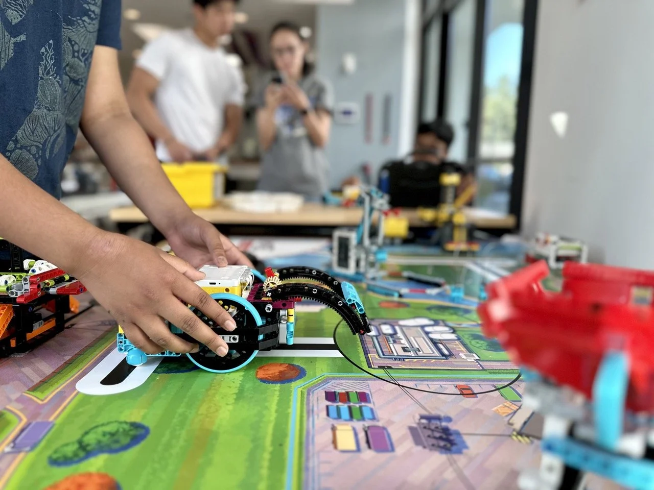 A student carefully positioning his LEGO robot on the FIRST LEGO League challenge field, preparing for a practice match.