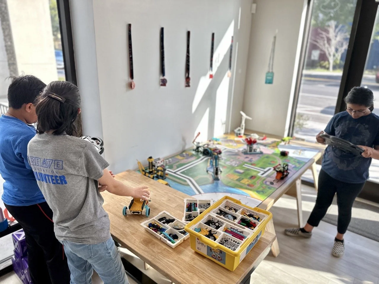 A robotics coach guiding students through the FIRST LEGO League challenge field, explaining key mission elements and robot strategy.