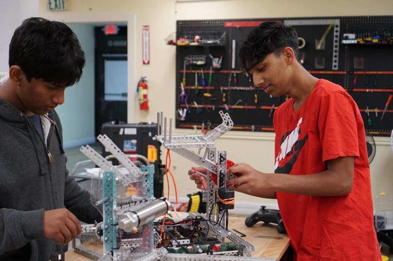 A young roboticist carefully adjusting the lift mechanism on his VEX robot, ensuring optimal performance for the competition.