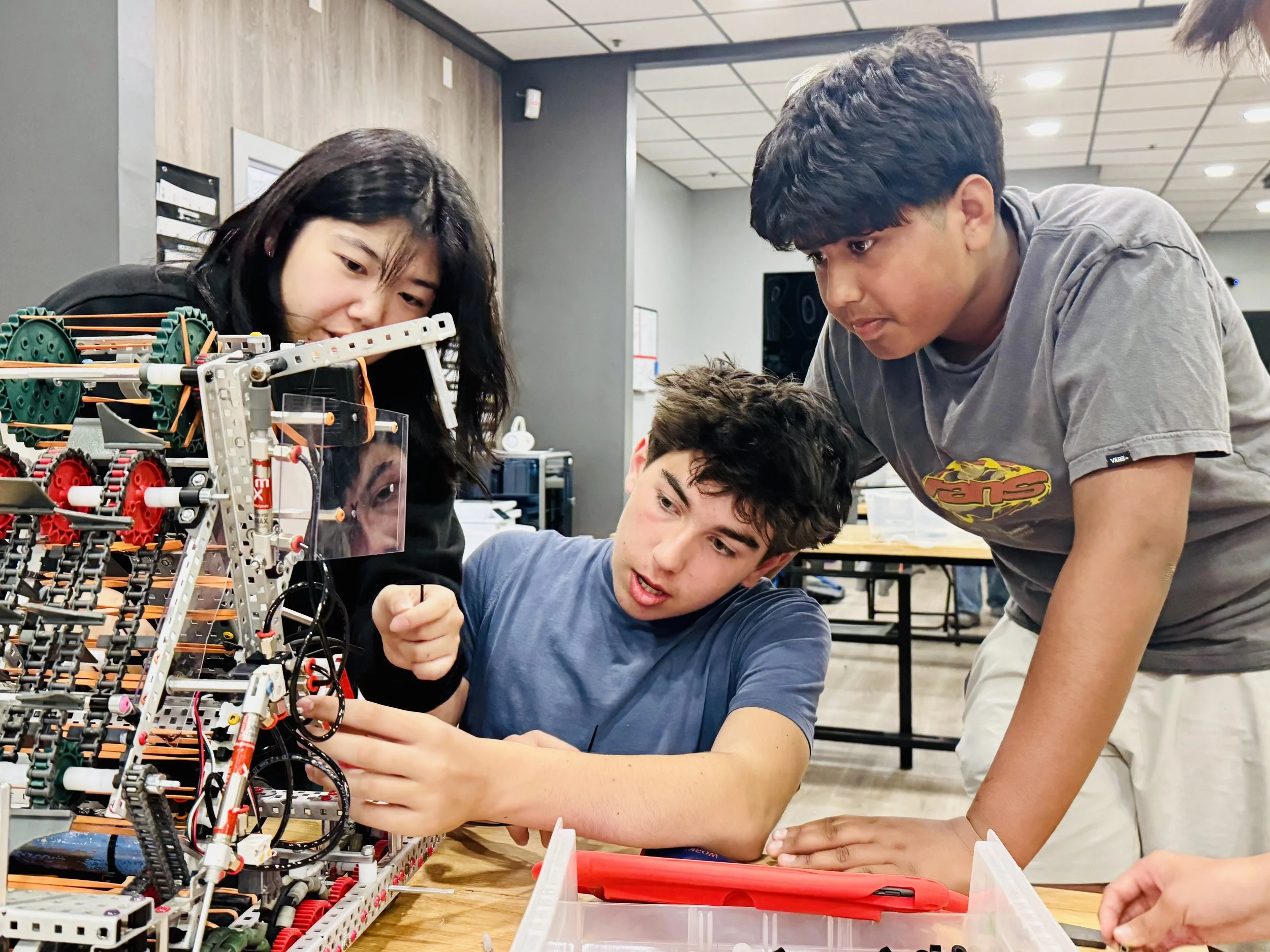 Robolabs students collaborating to build and refine a VEX AI robot, gaining hands-on experience in mechanical engineering, programming, and autonomous robotics.