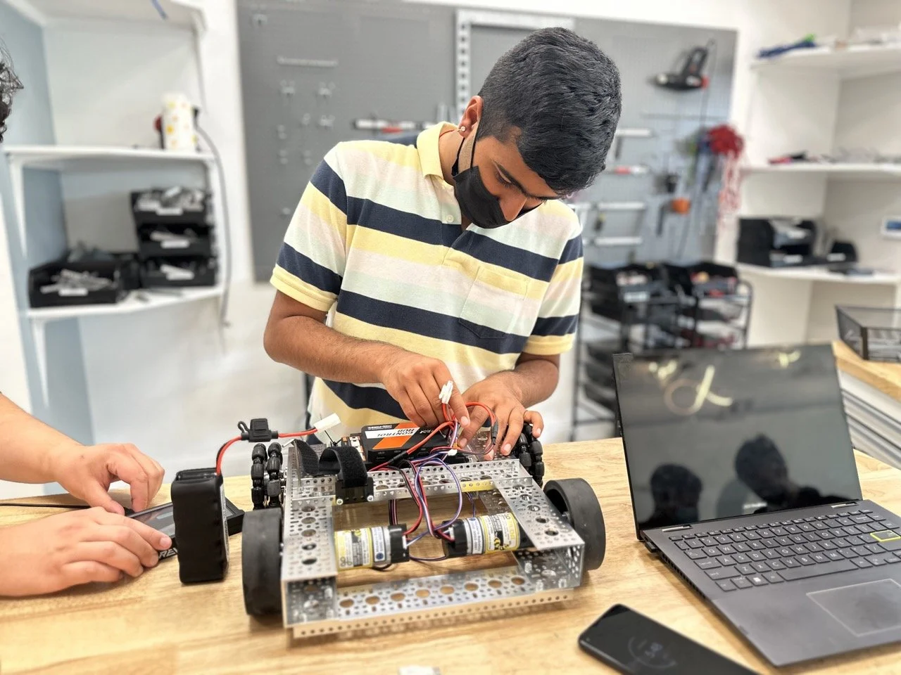 A student focused on wiring the electronics of his FIRST Tech Challenge robot, ensuring proper connections for motors and sensors.