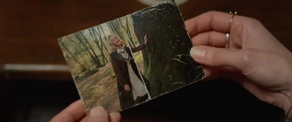 The character of Fiona in Hokum (2026) holding a picture of Ohm's mother standing by a tree in Ireland