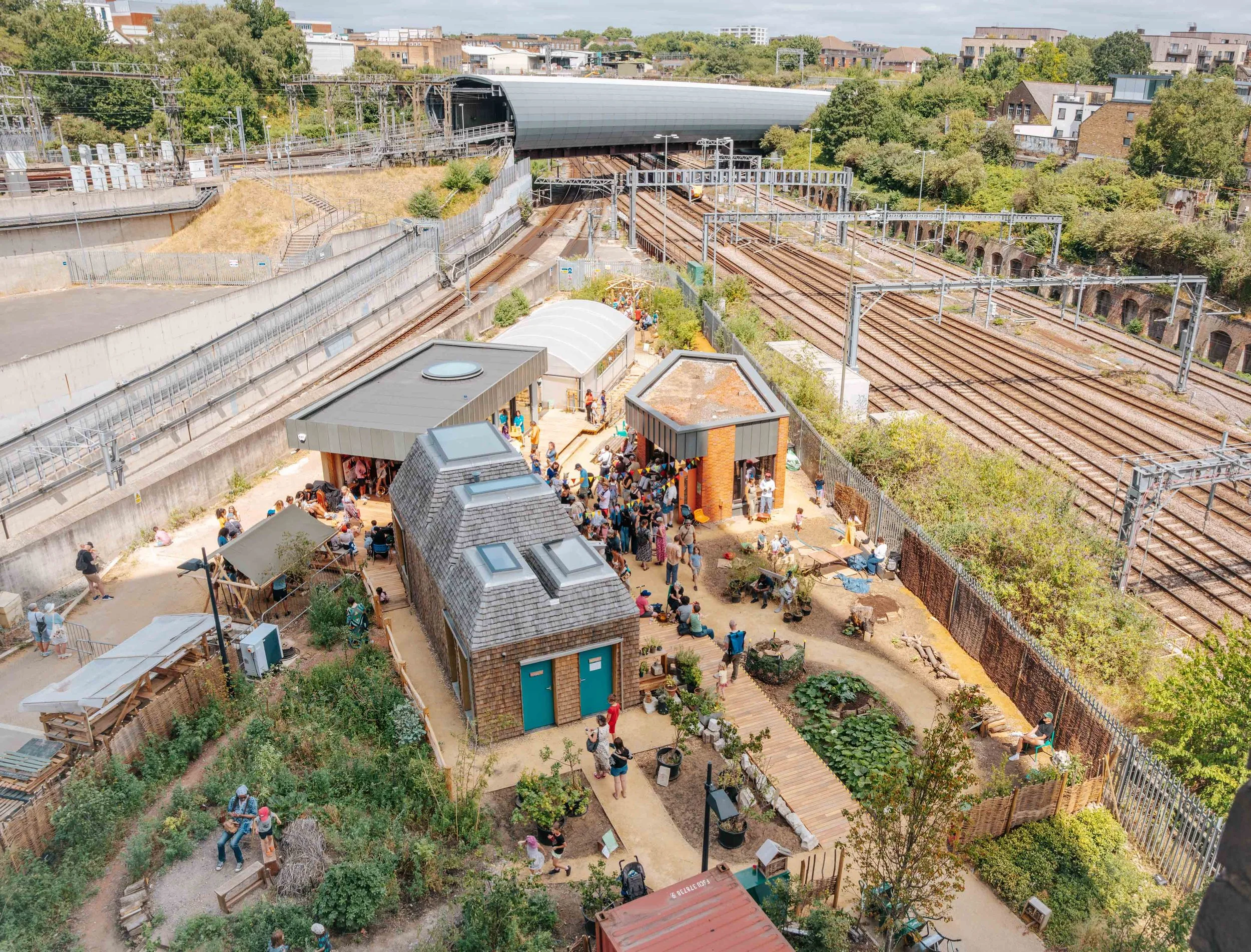 An aerial view of the Story Garden showing three buildings, a polytunnel and growing spaces nestled between two train tracks