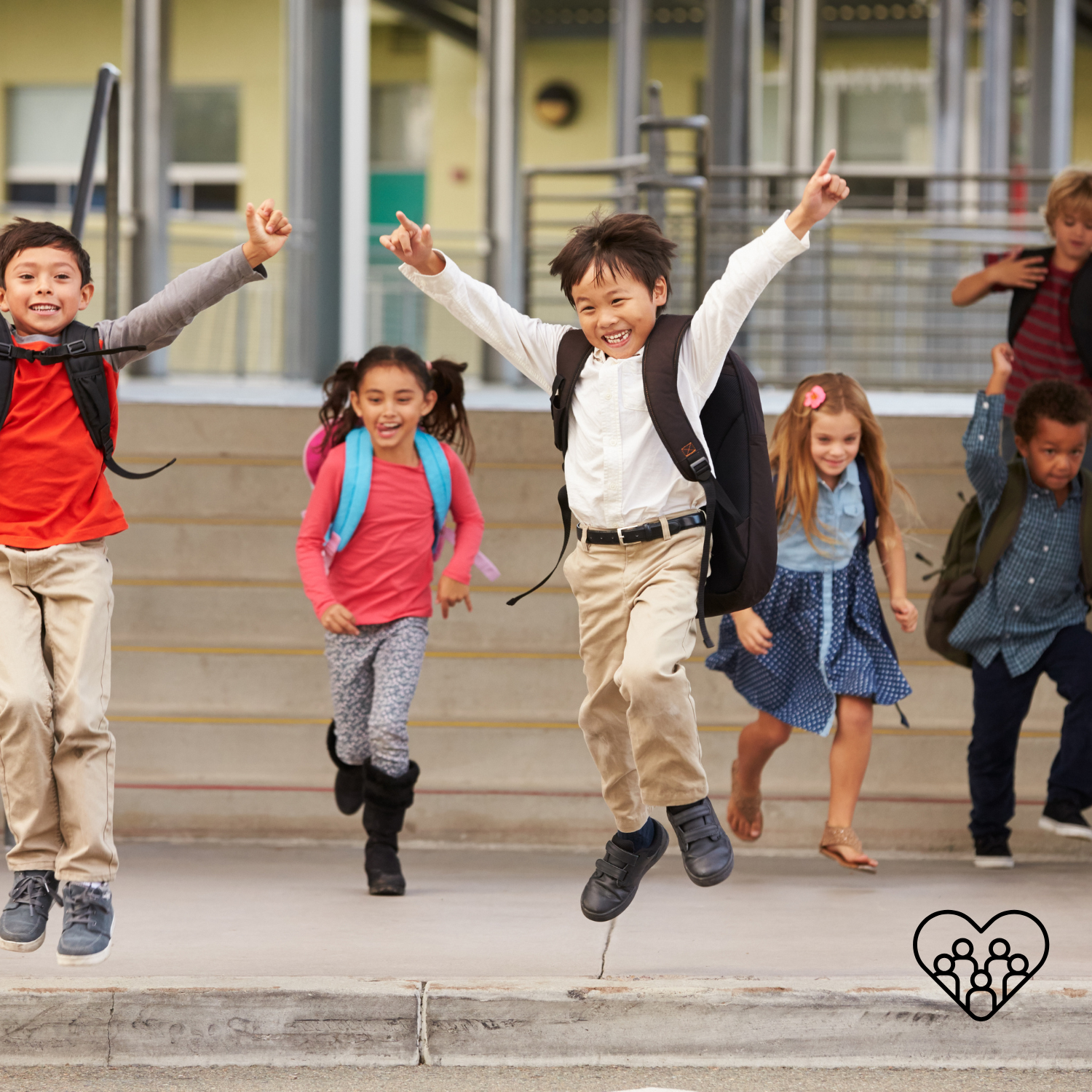 A group of six children with backpacks jumping and smiling on school steps.