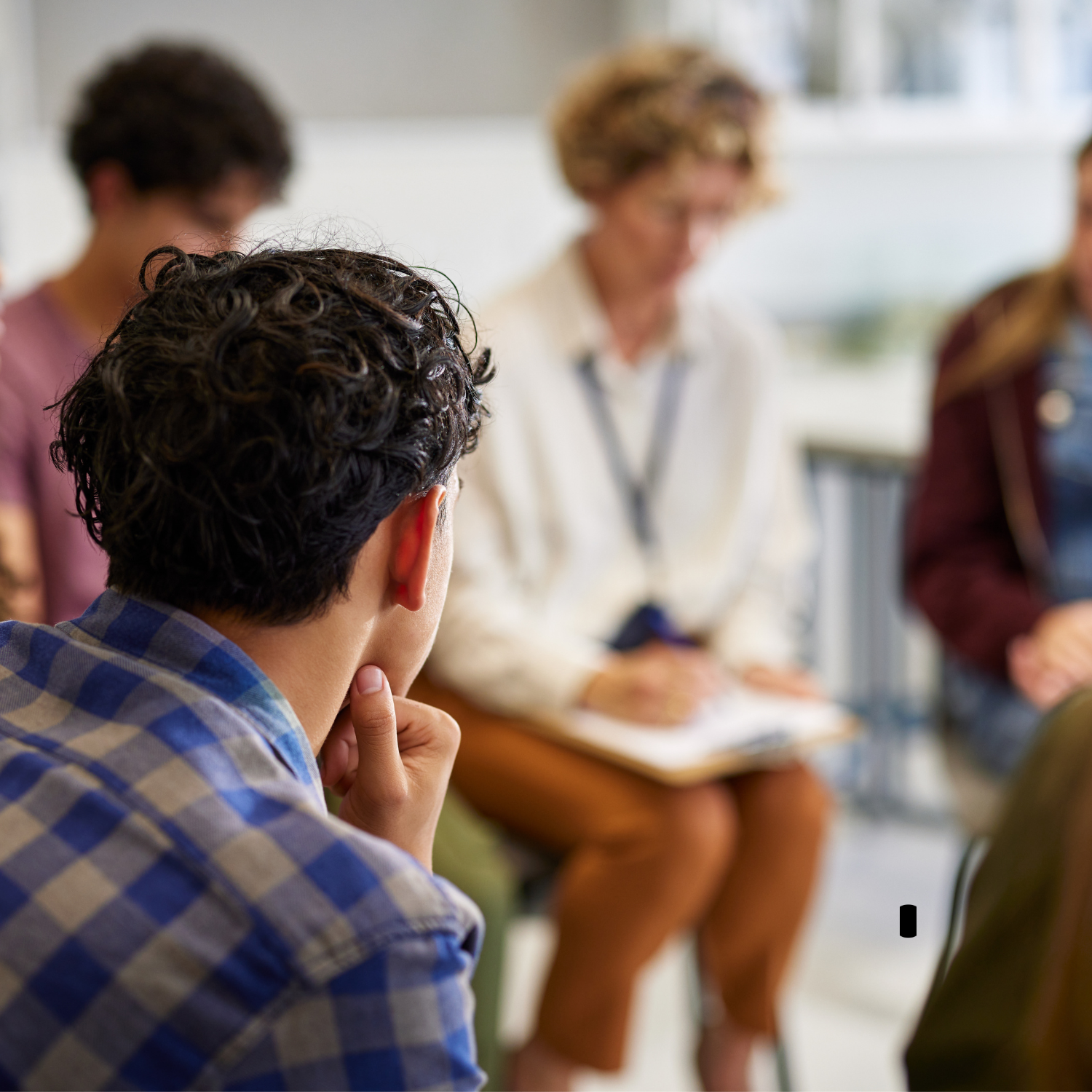 Person sitting with hand on chin attending a group discussion or meeting