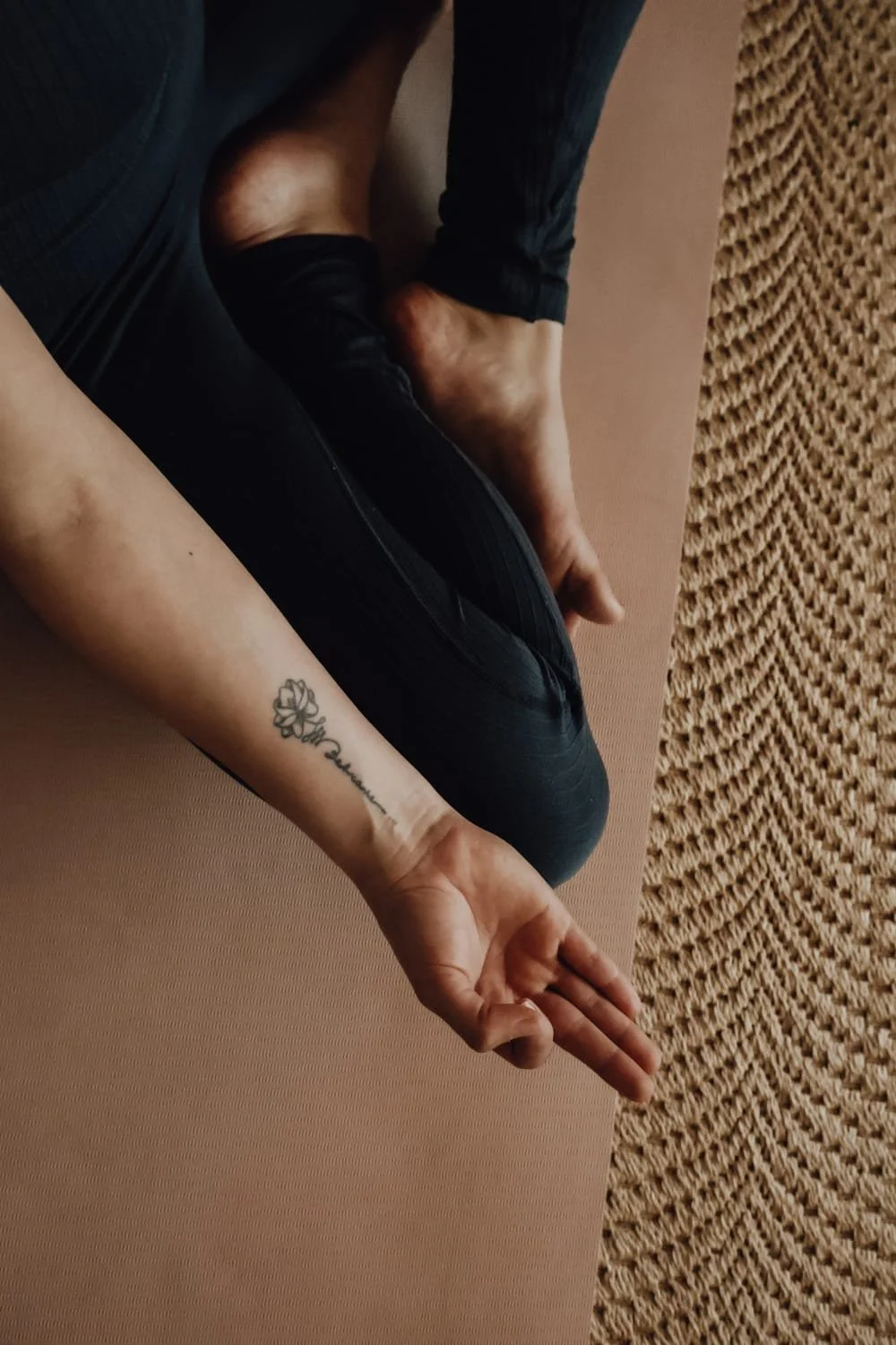 Eine schwangere Person hält ihre runde Bauch in einer grünen Kleidungsjacke mit einer Hand, während sie die andere Hand auf den Bauch legt, vor einem Holzschrank.