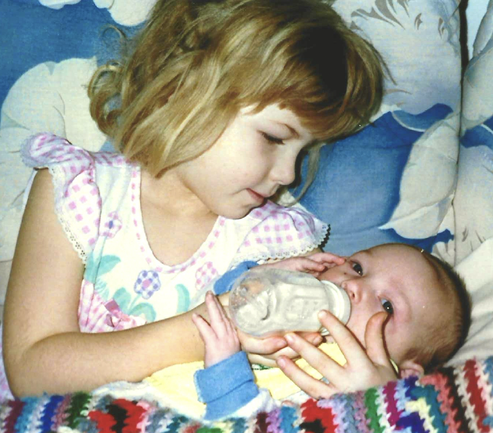 A little girl feeding her baby brother a bottle