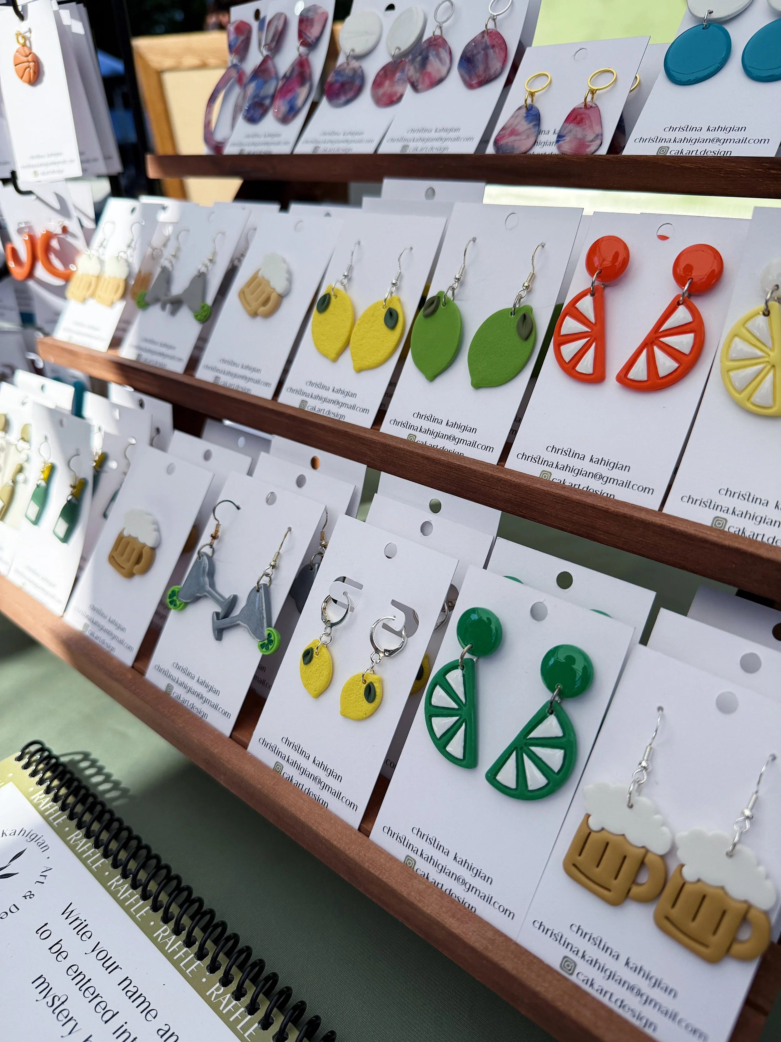 Display of colorful handmade earrings on a jewelry stand at a craft fair.