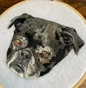 Close-up of hand embroidered pug portrait using thread painting techniques