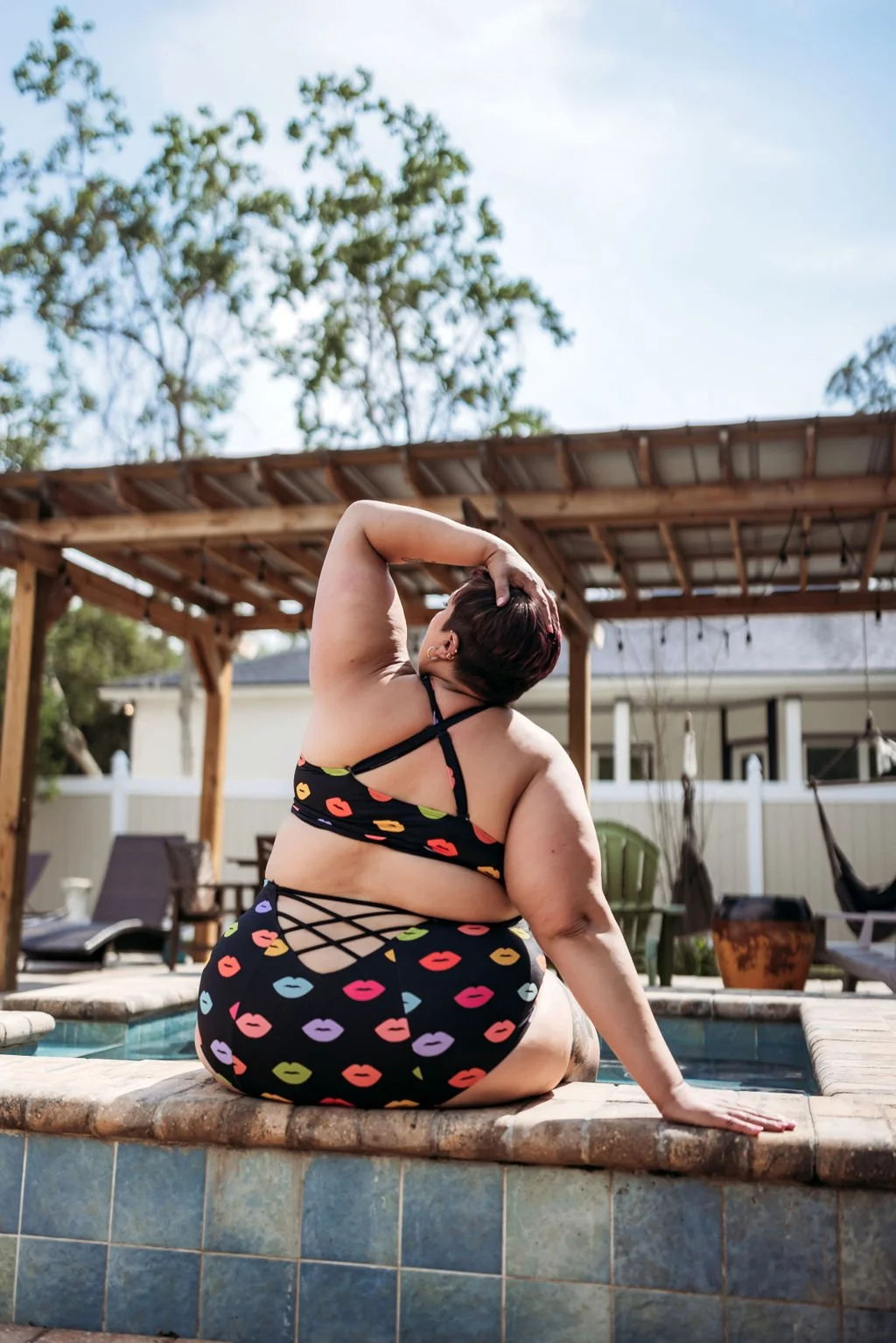 Woman in colorful swimwear posing beside a pool during an outdoor boudoir session in Jacksonville, Florida