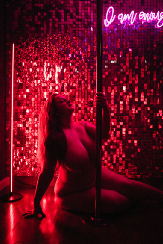 Silhouette of a woman seated beside a pole against a red sequined backdrop.