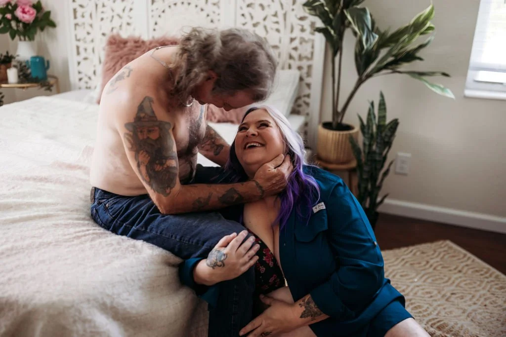 Older couple laughing together beside a bed during their Jacksonville boudoir session