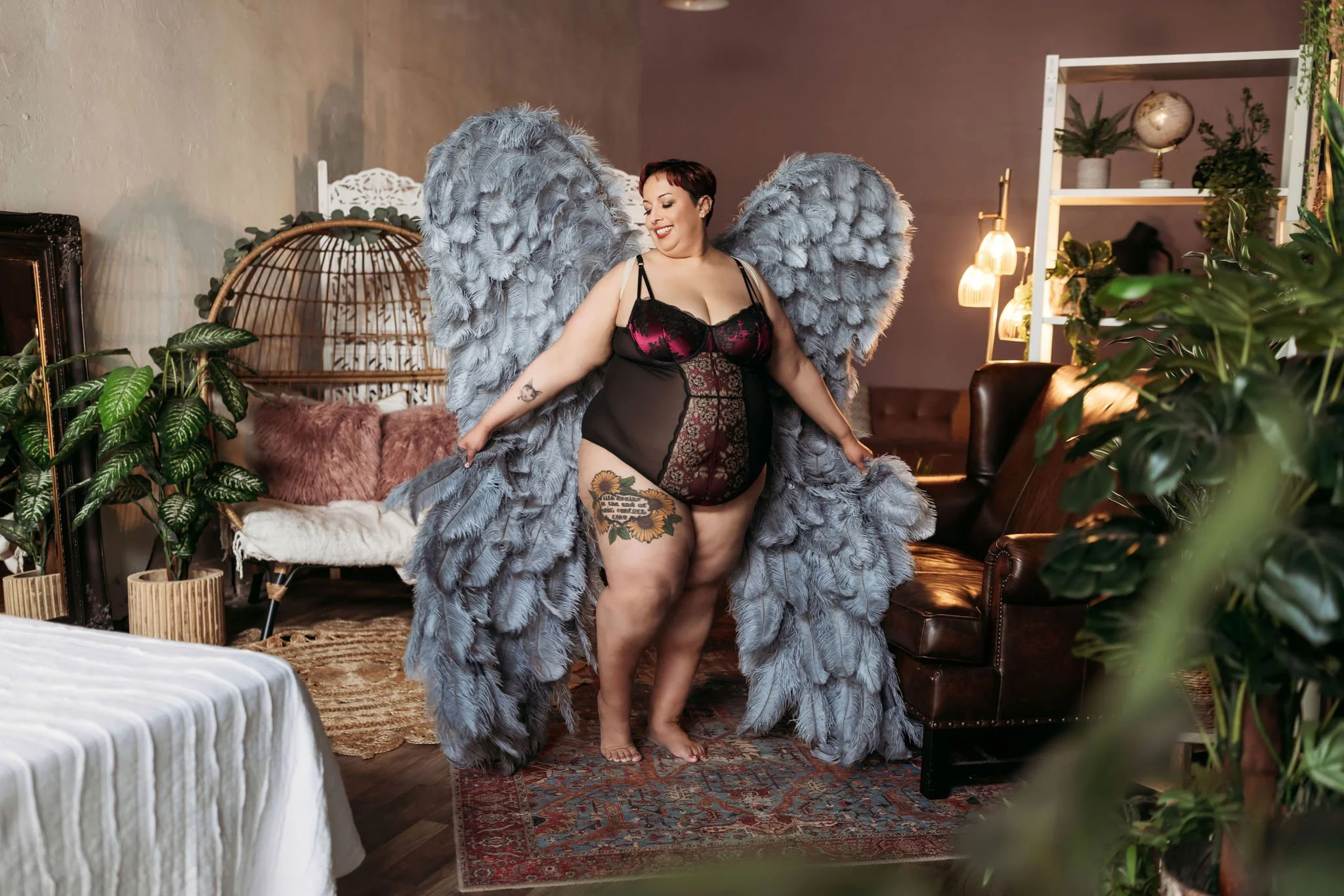 Woman wearing black and burgundy lingerie posing with large gray angel wings at Hype Girl Boudoir