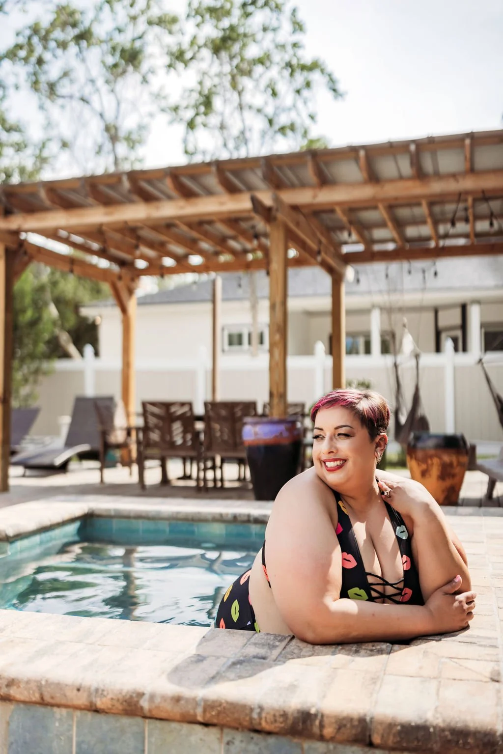 Woman in colorful swimwear posing beside a pool during an outdoor boudoir session in Jacksonville, Florida