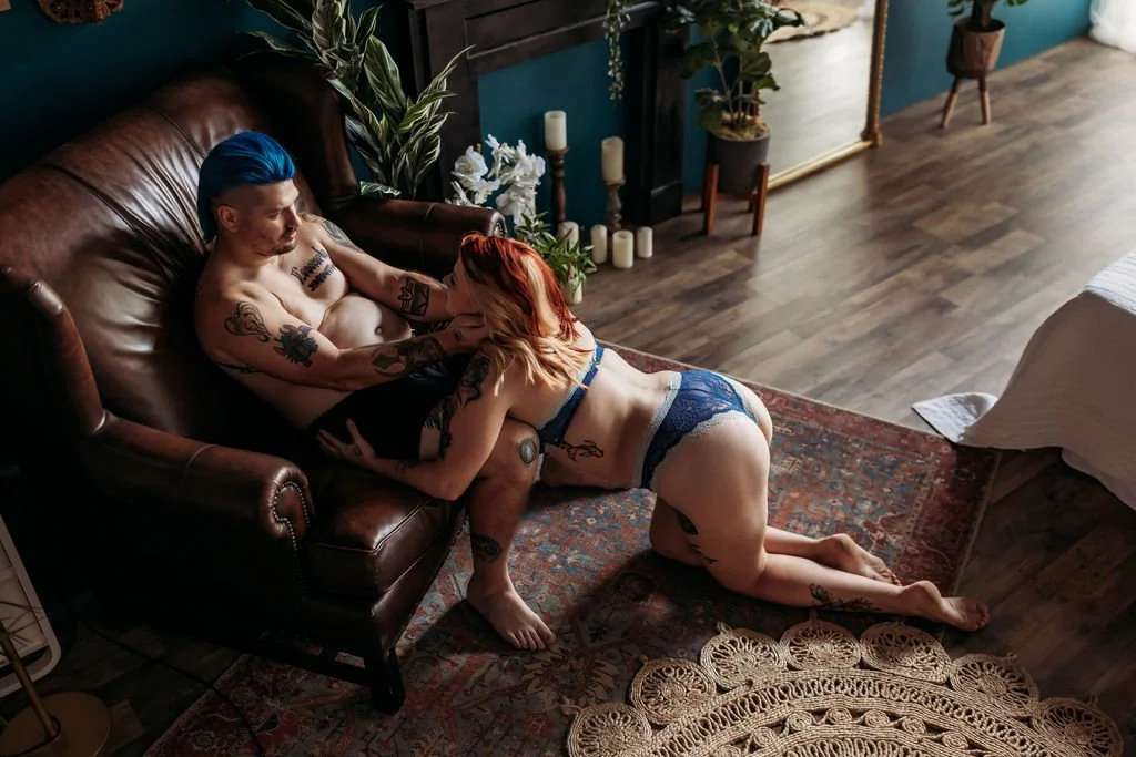 Tattooed couple looking at each other while posing together on a couch