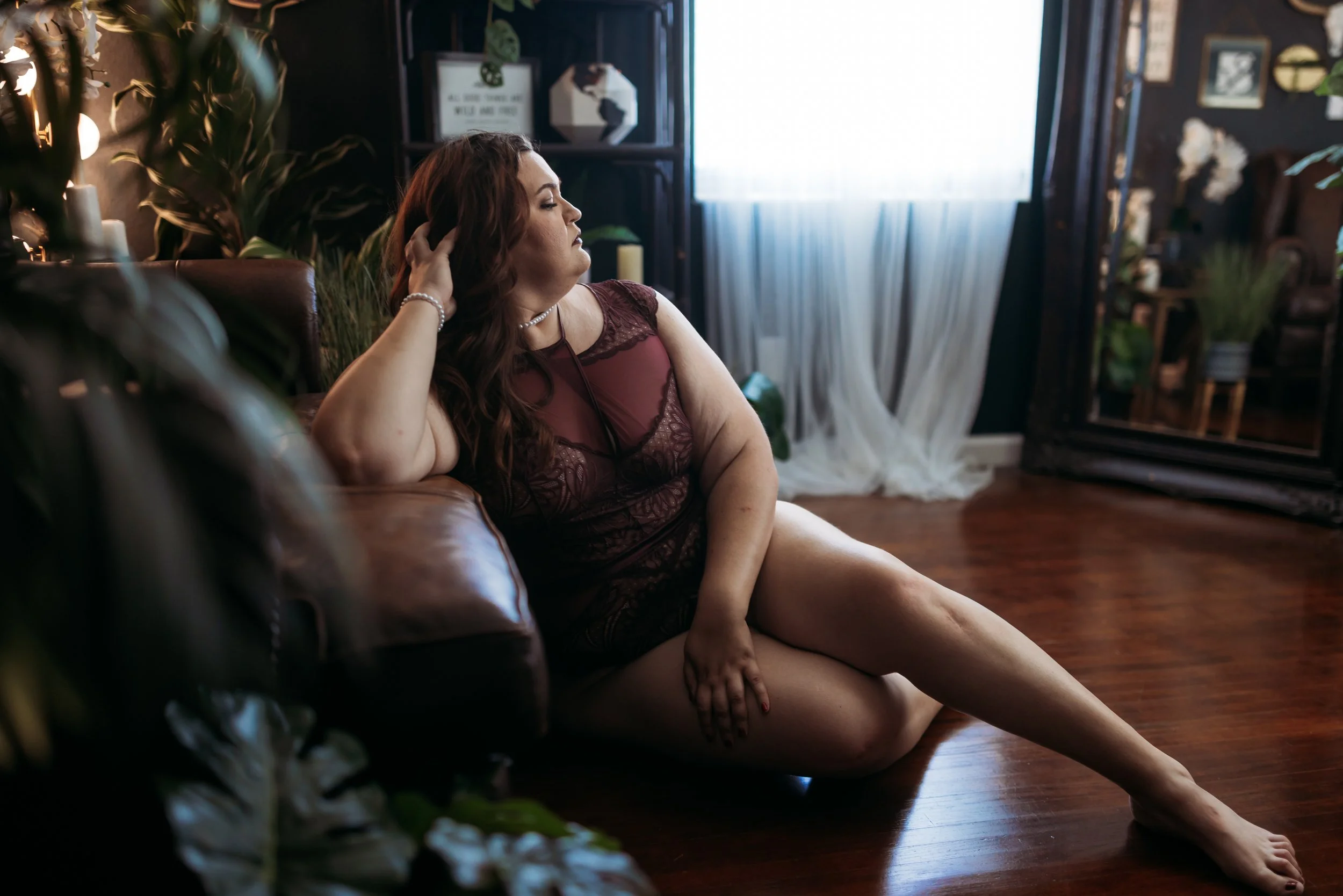 Plus-size woman in burgundy lingerie posing on the floor during a Hype Girl Boudoir session in Jacksonville