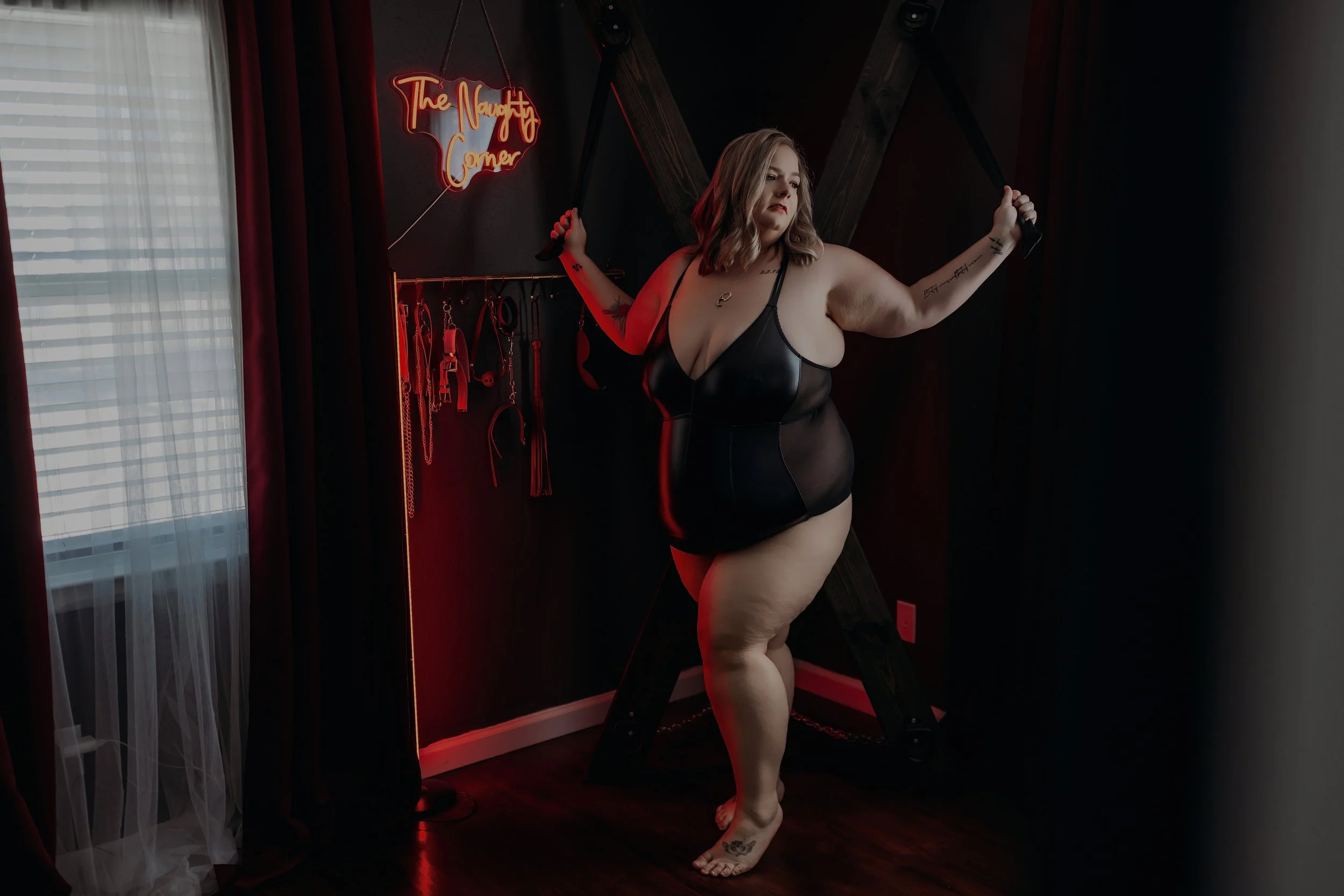 Woman in a black bodysuit posing in the dungeon set at Hype Girl Boudoir in Jacksonville, Florida