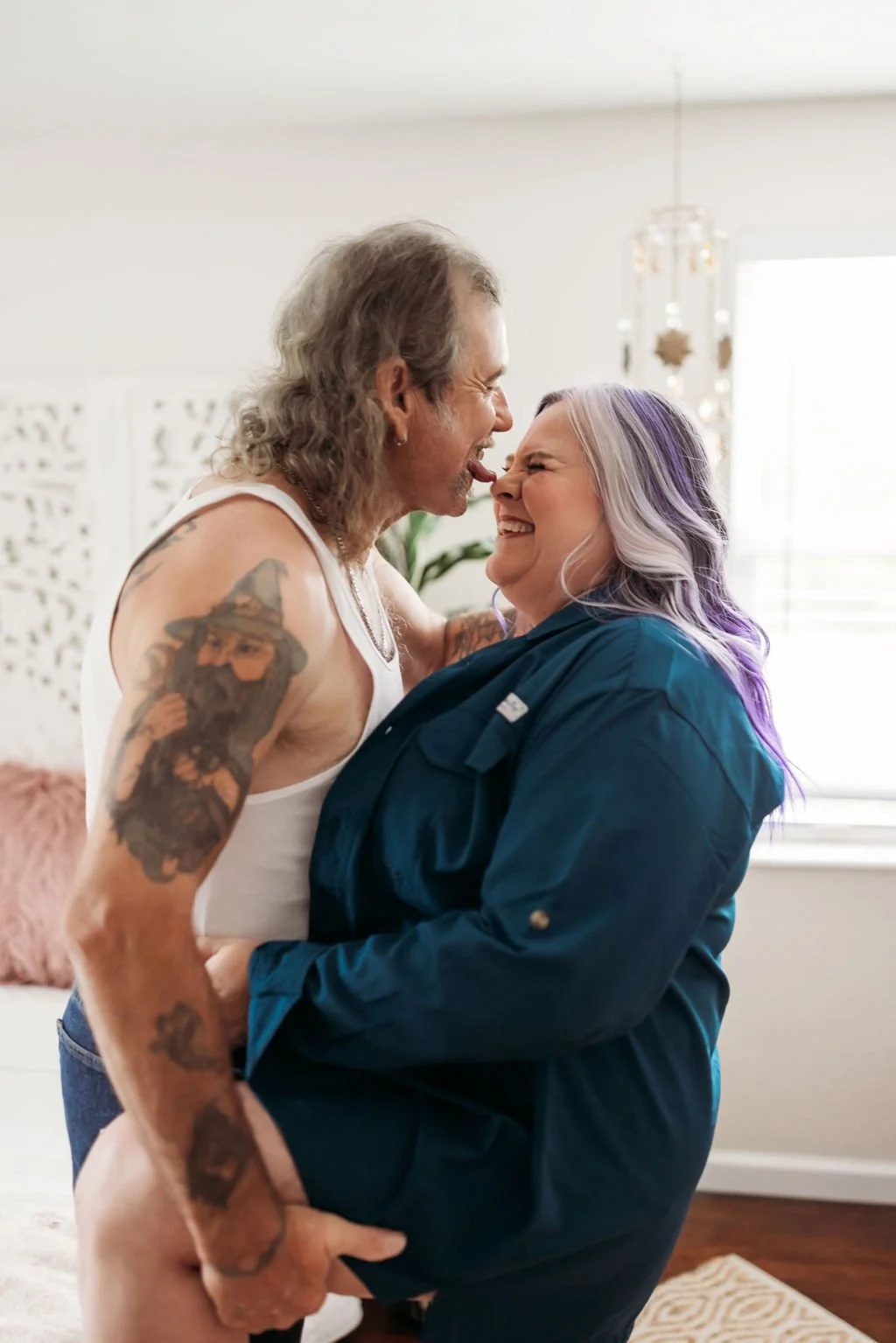 Older couple laughing together while posing in a blue shirt during their couples boudoir session
