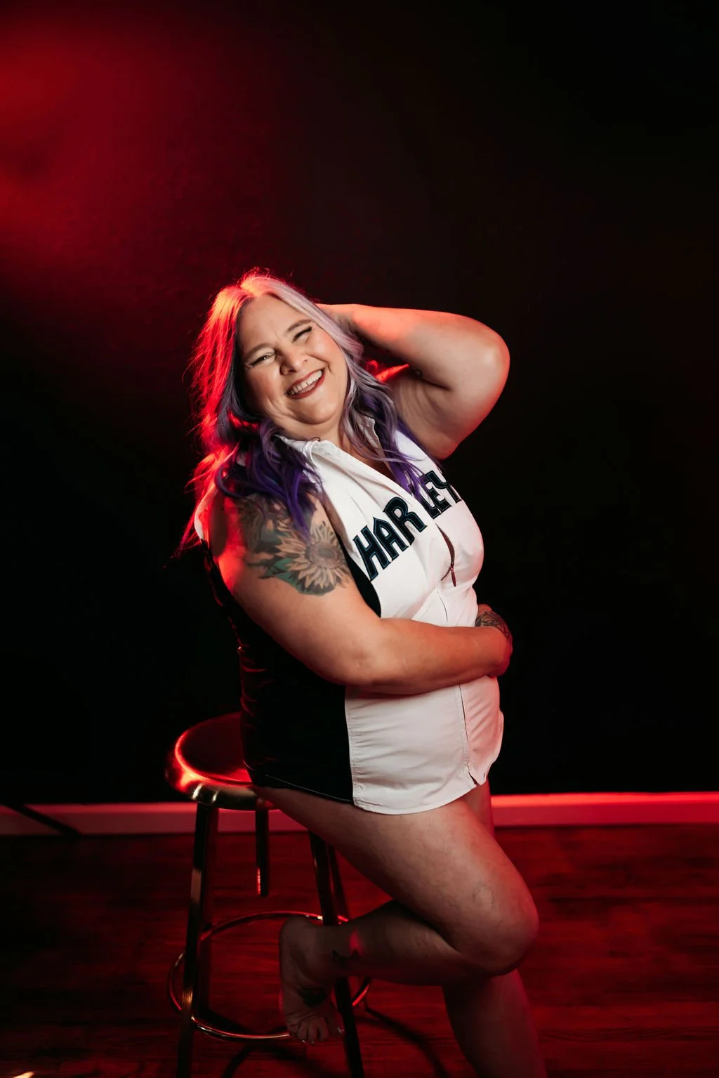 Woman laughing in a Harley Davidson top during her red-light boudoir session in Jacksonville