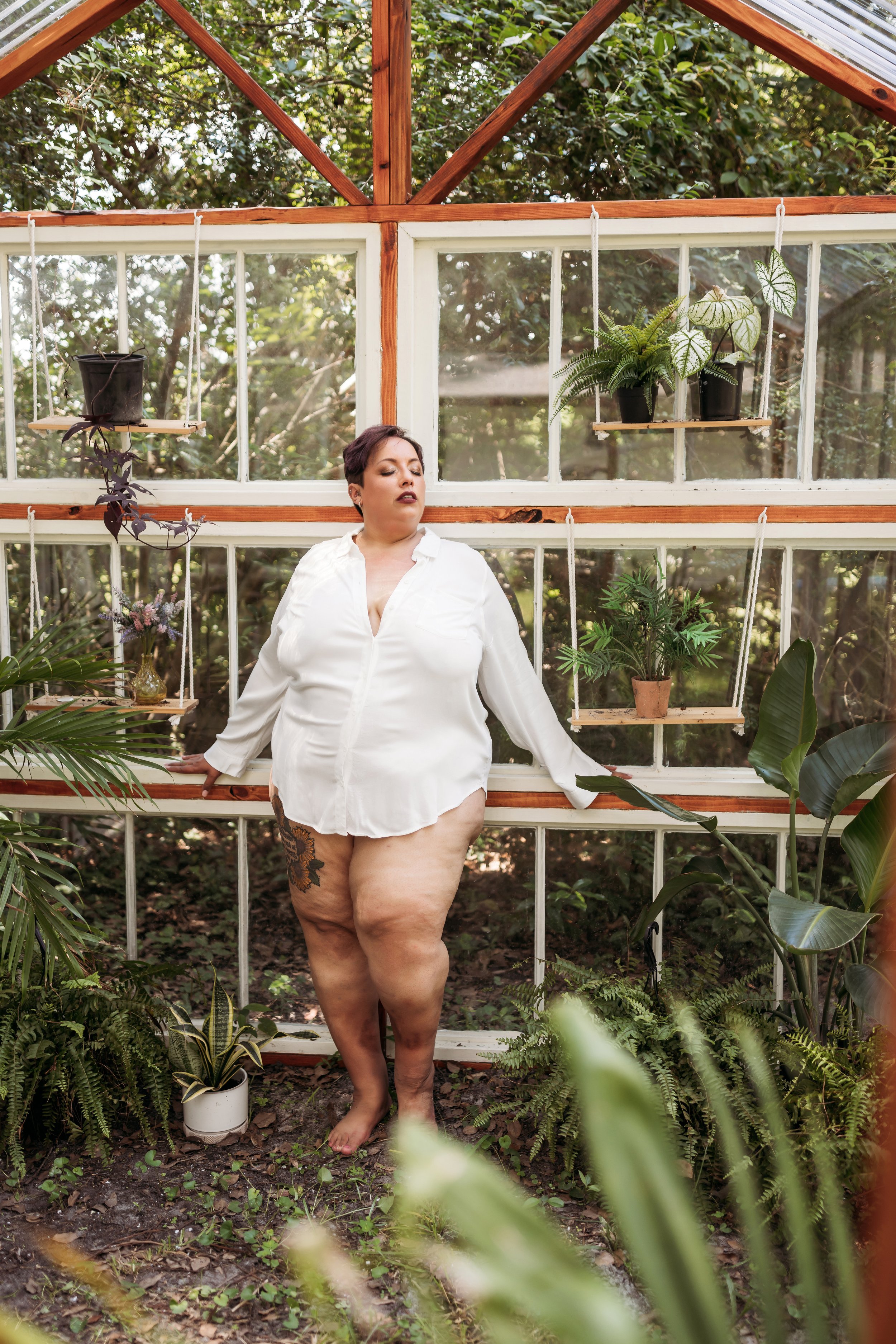 Woman posing in an oversized white shirt during a greenhouse boudoir session in Jacksonville, Florida