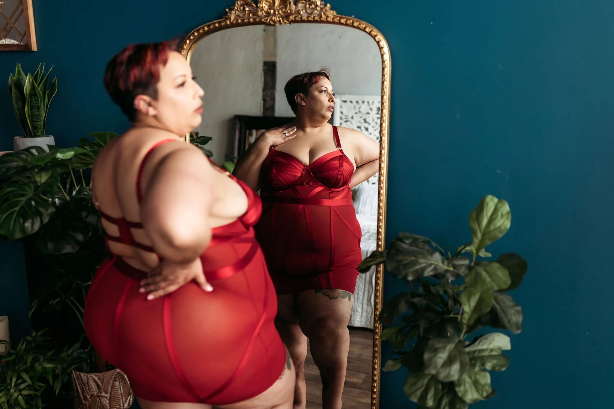 Plus-size woman in red lingerie posing in front of a gold mirror during a Jacksonville boudoir session