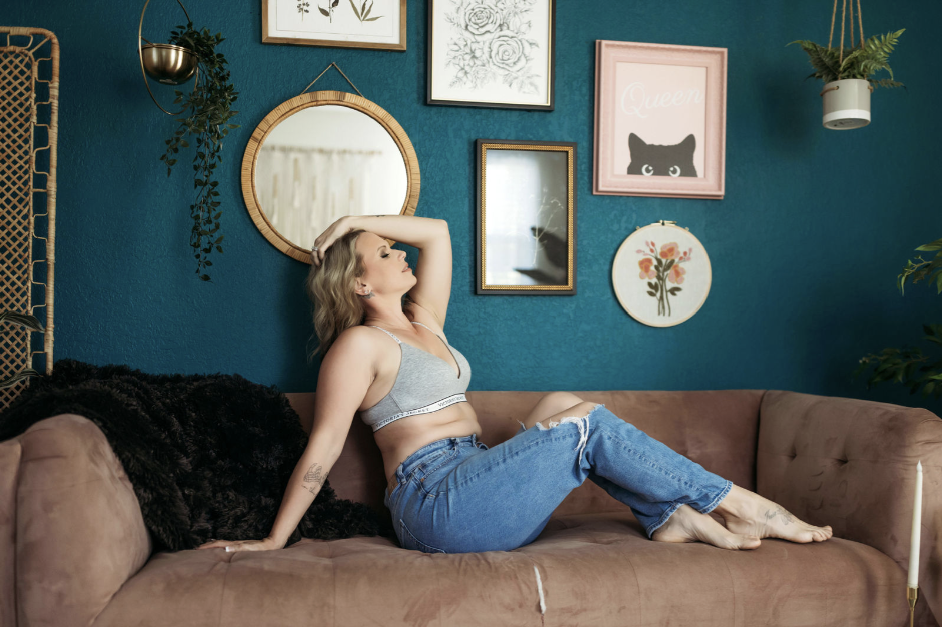 Woman reclining on a studio sofa in jeans and a gray bralette.
