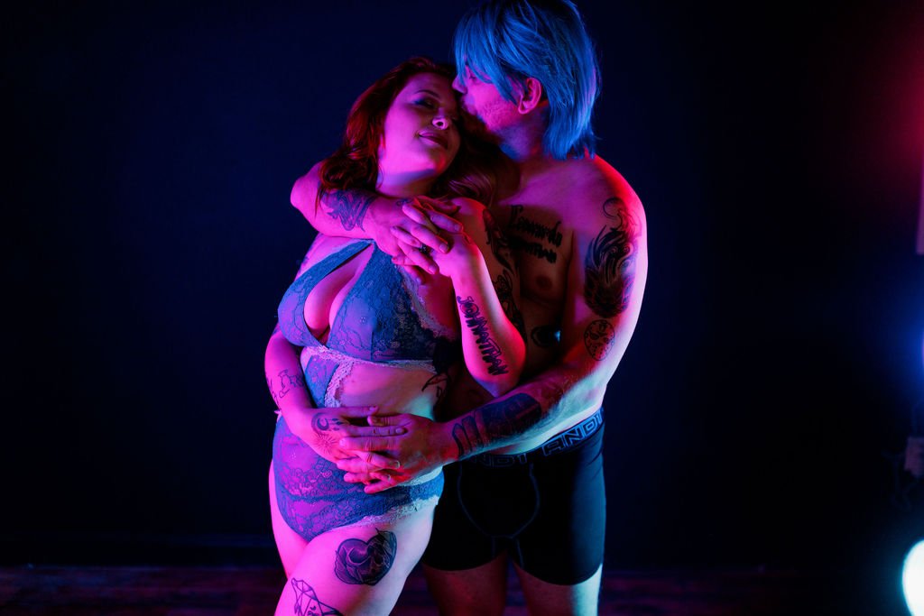 Tattooed couple embracing during a creative neon couples boudoir session in Jacksonville